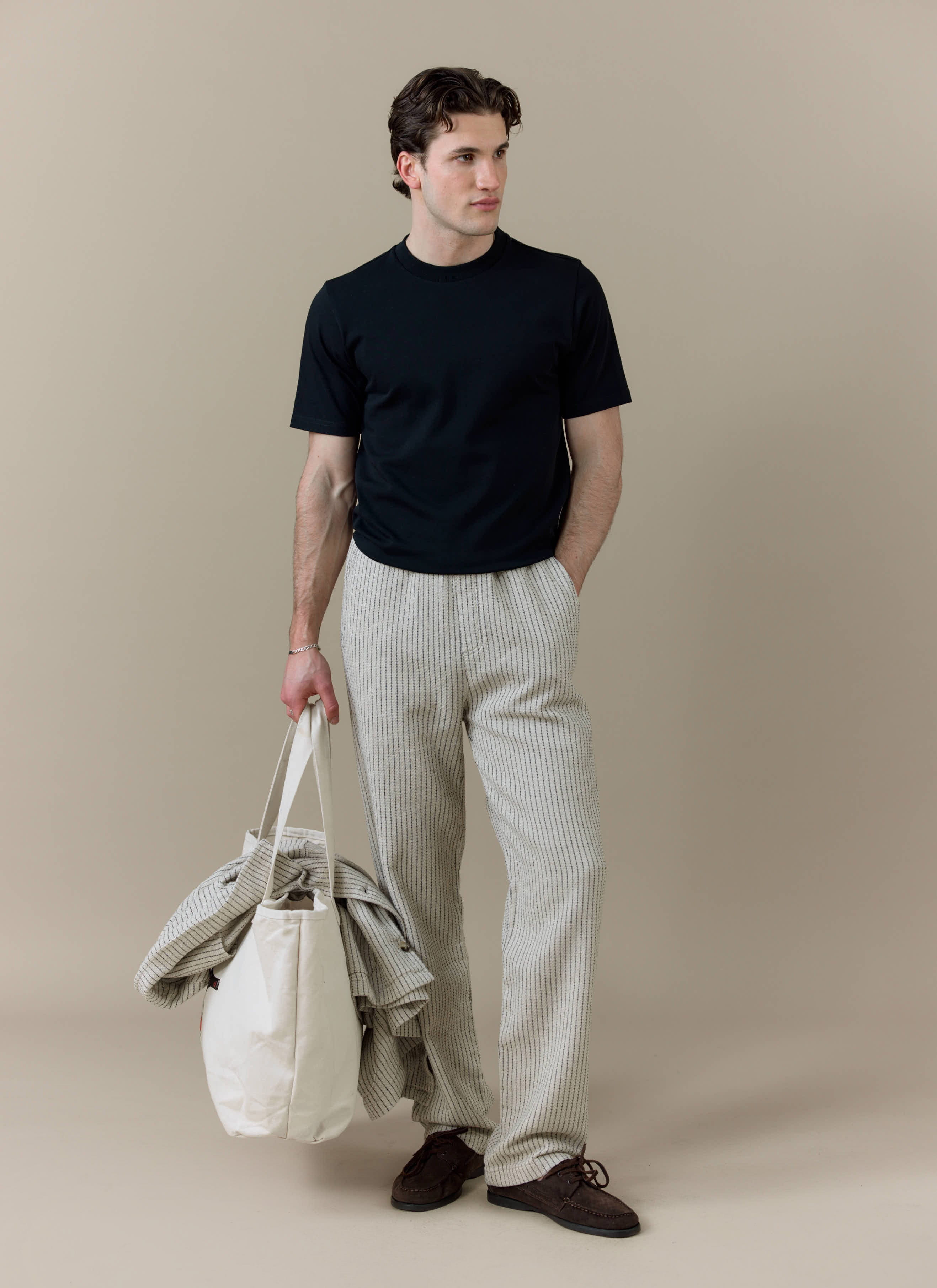 A model wearing the Percival Sorrento Wide Leg Trouser in cream linen, featuring a relaxed, straight leg fit.