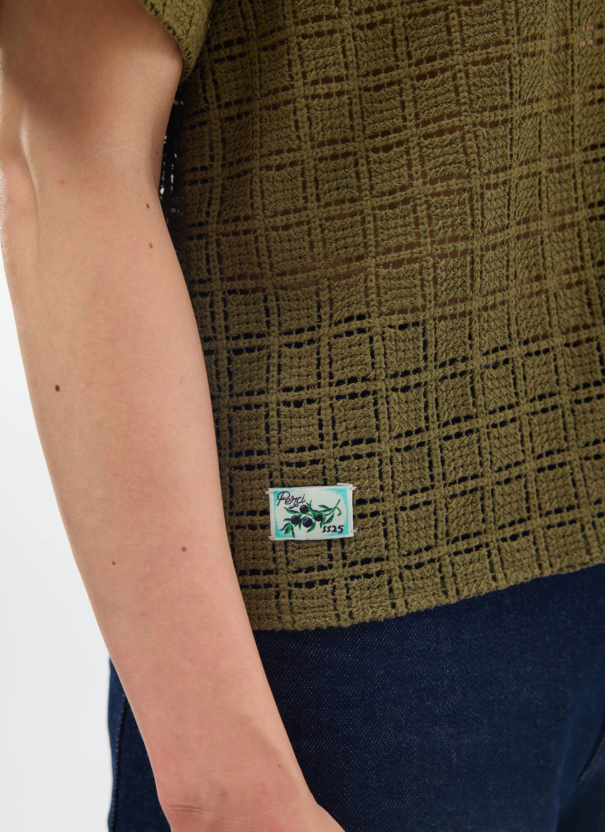 Close-up on the intricate crochet fabric and seasonal olive branch label on the Percival Palermo Cuban Shirt in olive green.