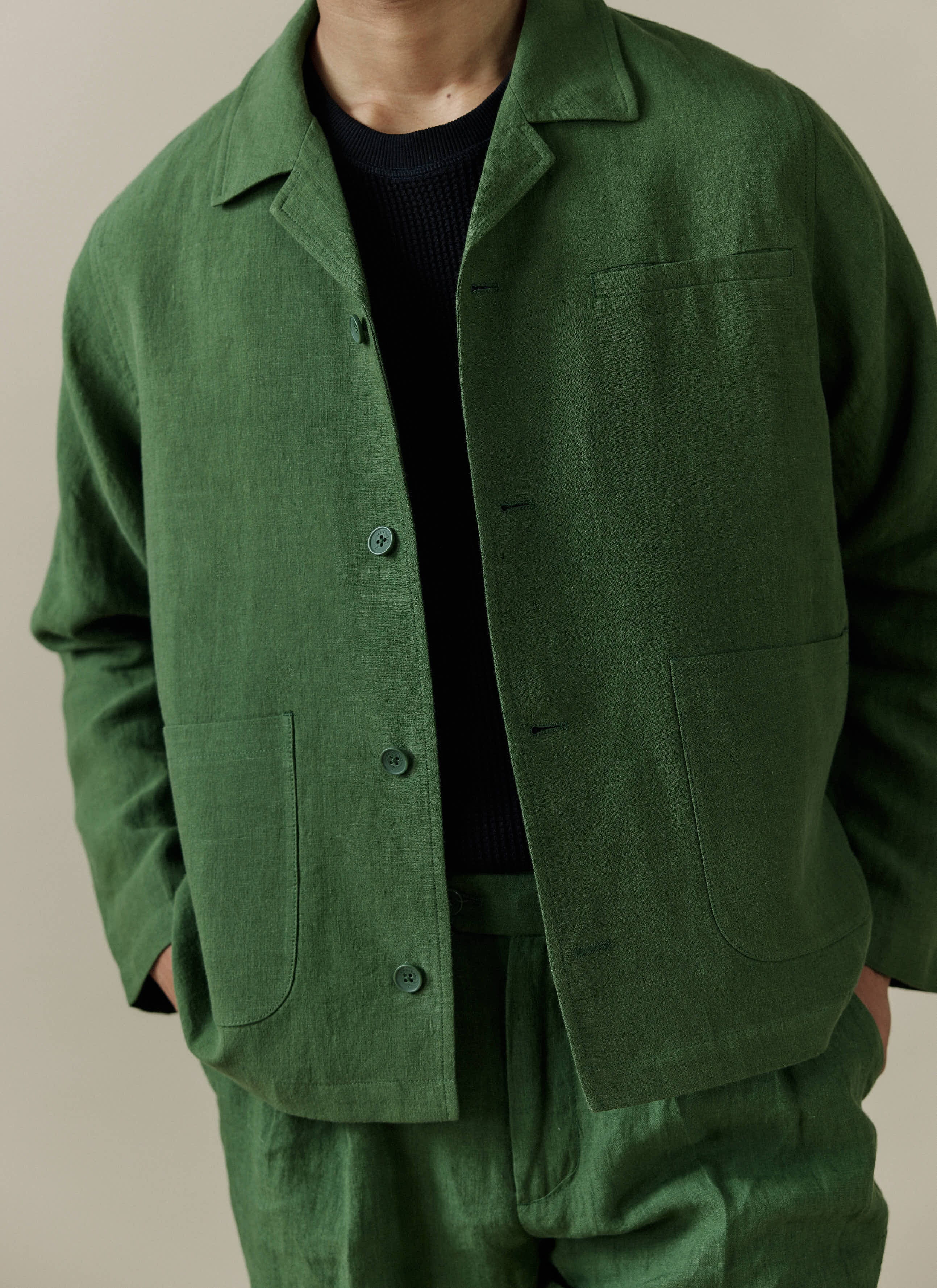 Close up of the Percival Linen Overshirt in Forest, styled over a black knit with matching trousers.