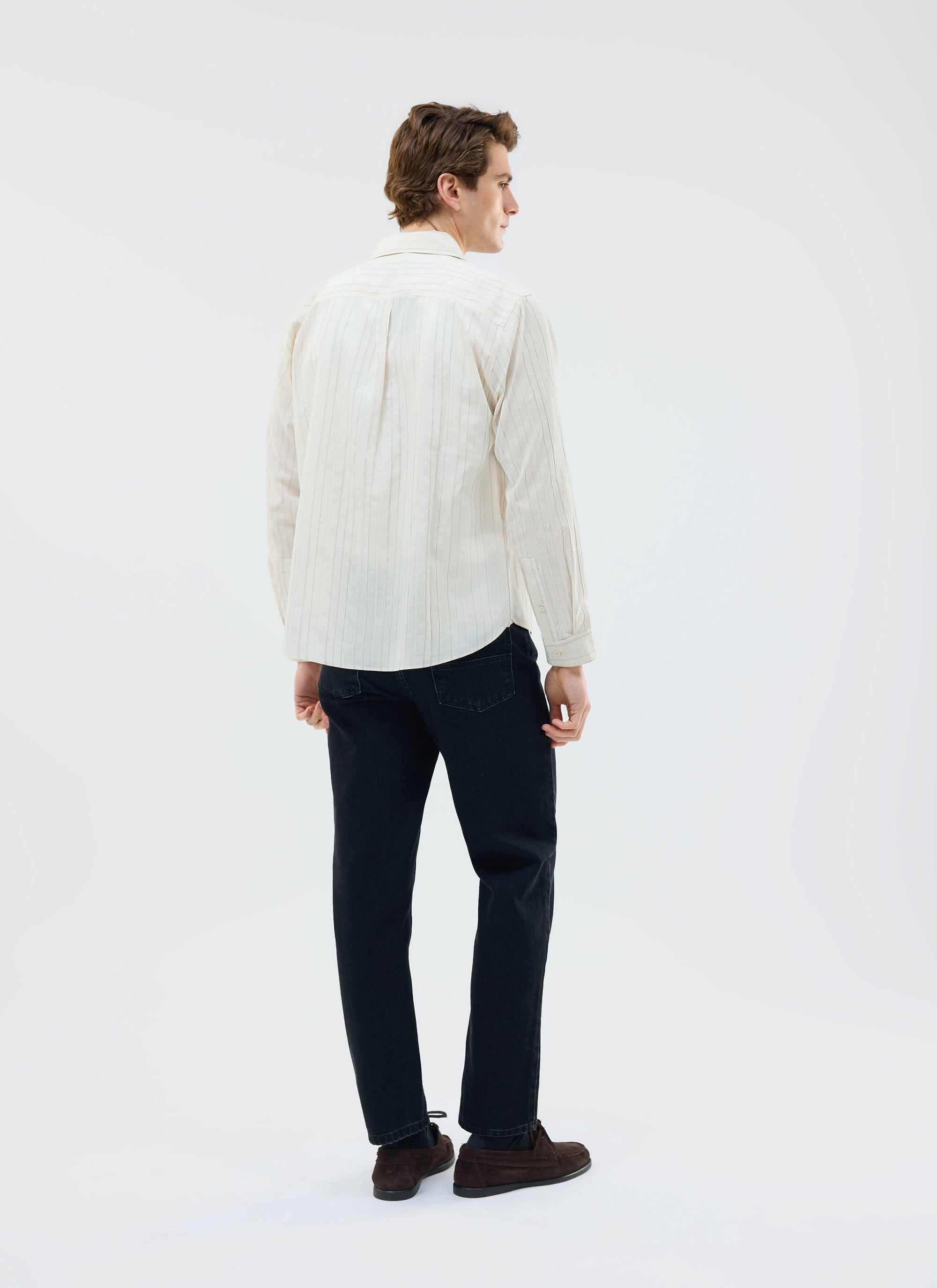 A model shot from behind wearing the Percival Lorenzo Pearce Shirt in ecru with black trousers.
