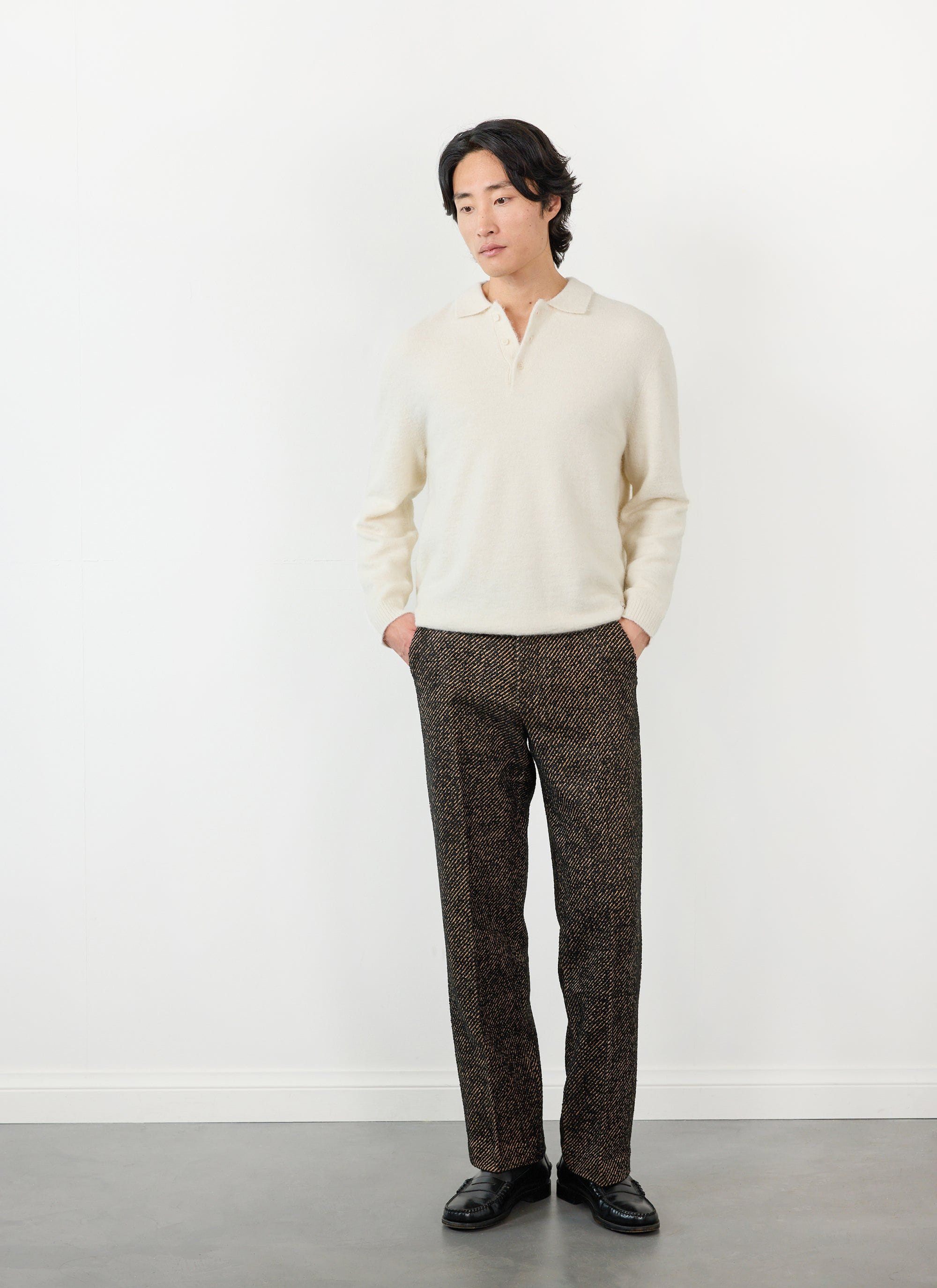 Model wears Percival's oak twill slack trousers with a cream knitted polo shirt.