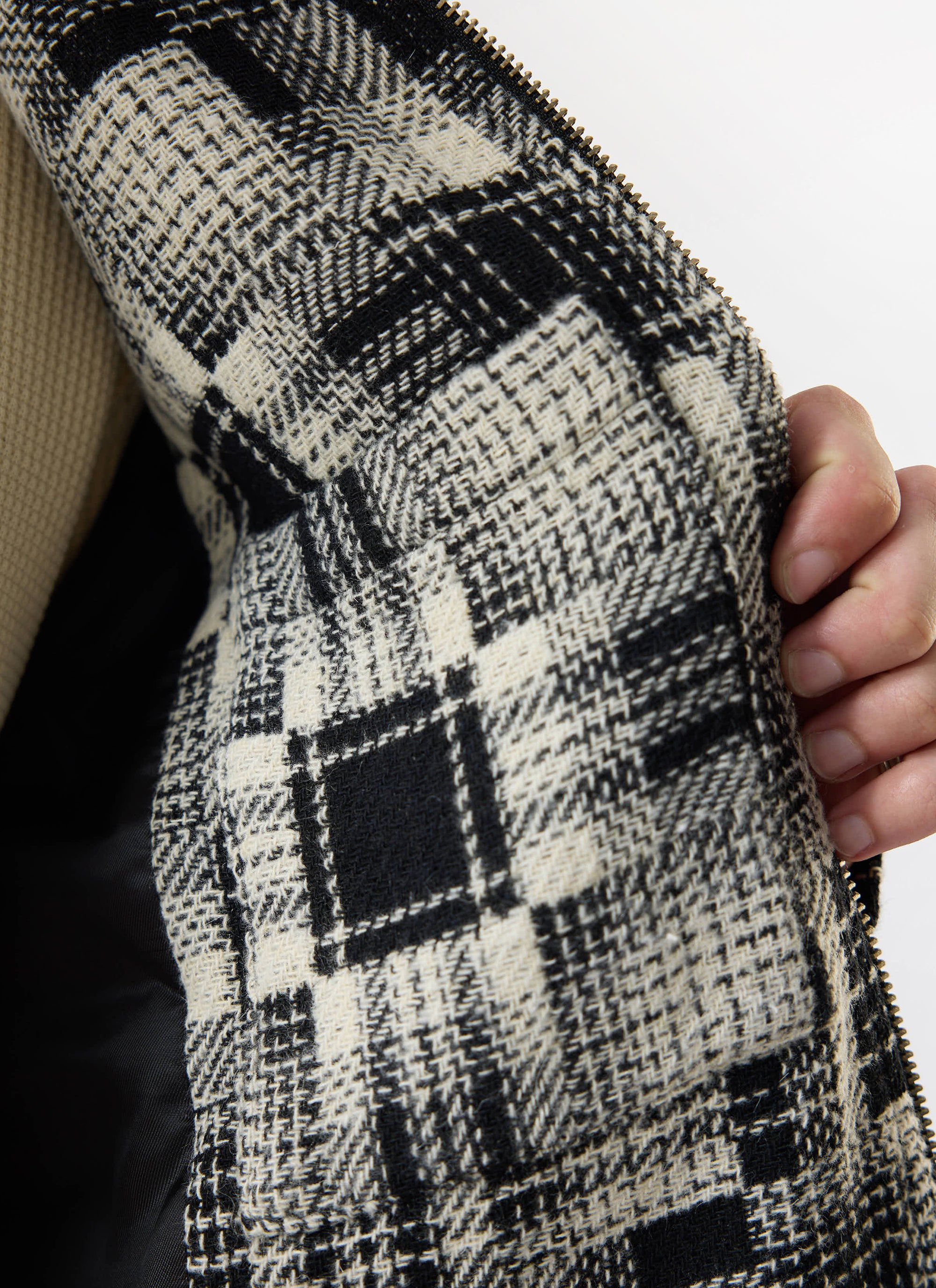 A close-up of the Percival Glossary Patchwork Jacket, showing the grey twill fabric and black lining.