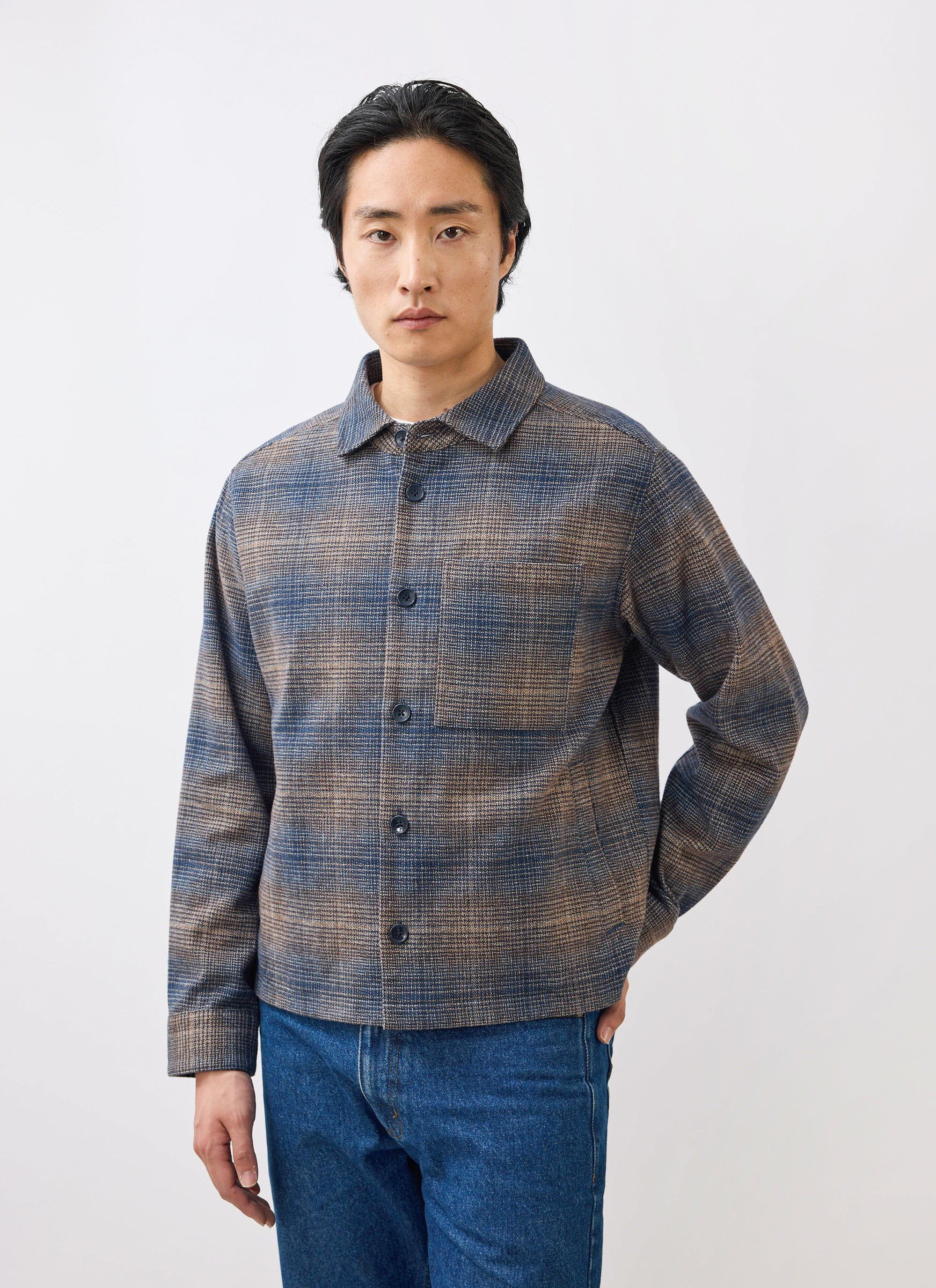 A man models the Percival Luton Check Overshirt in brown, a brushed cotton jacket, against a clean white studio background.