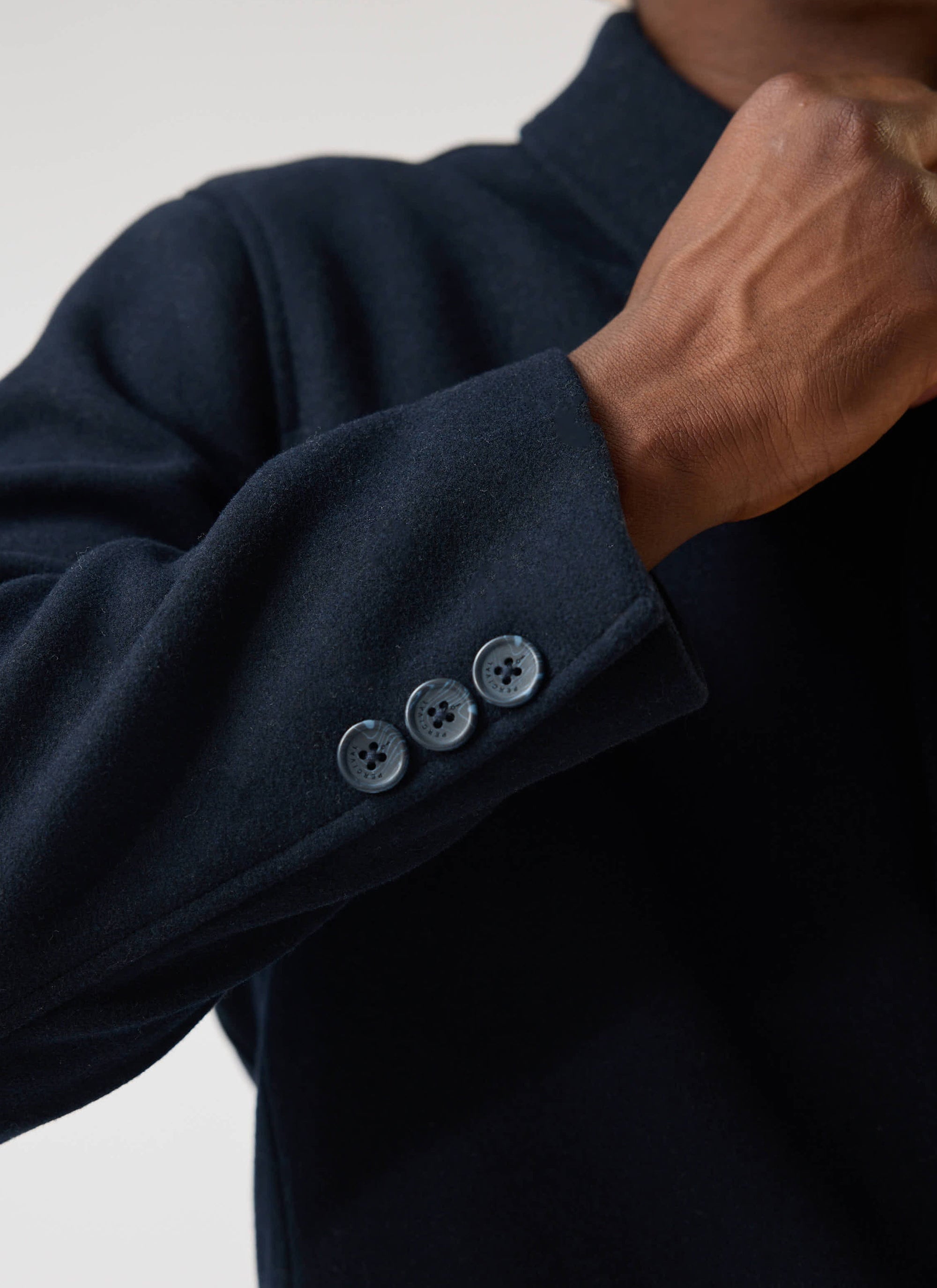 A close-up of the cuff on the Percival navy melton wool Peacoat, highlighting the branded button detailing.