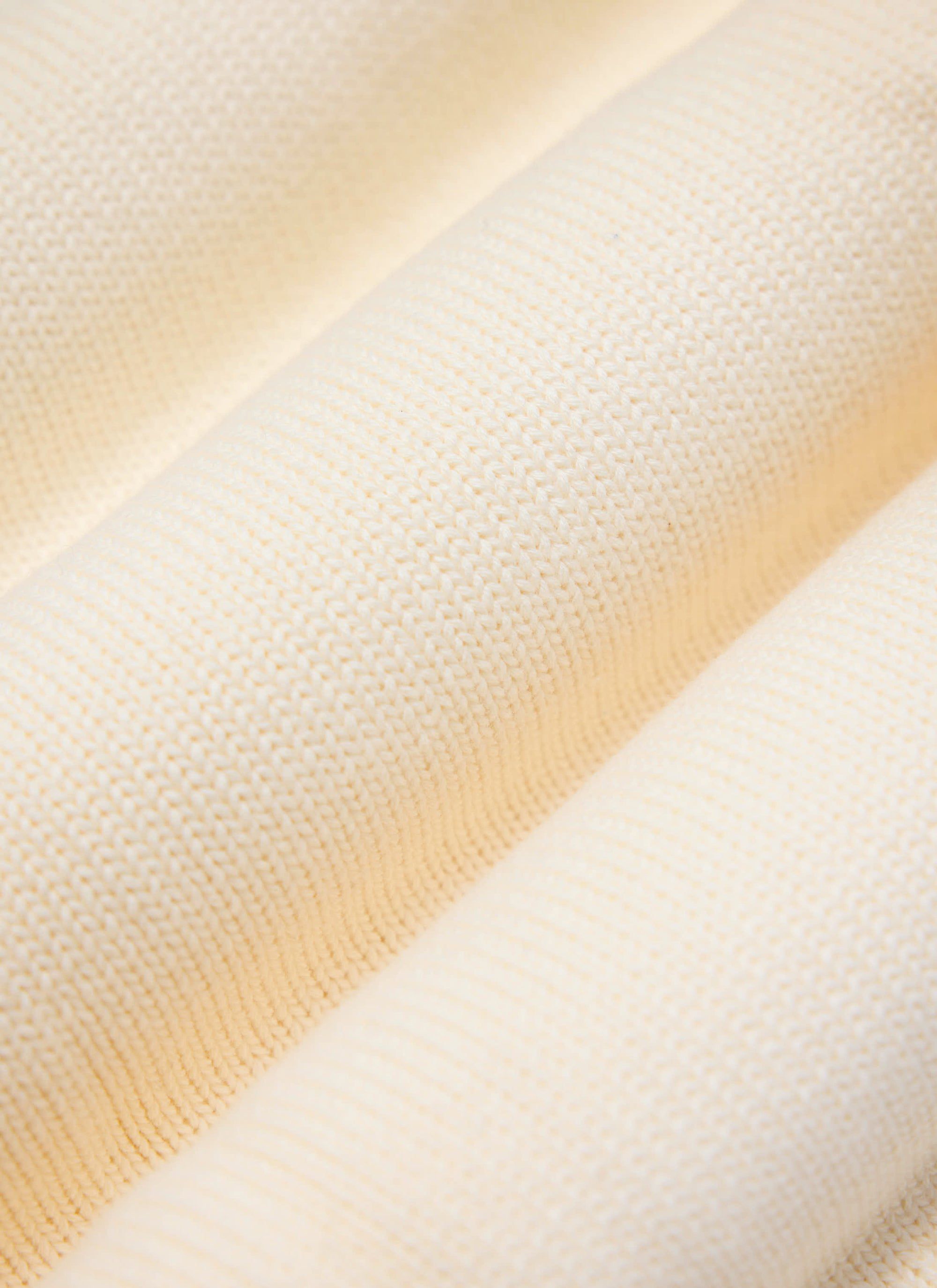 A close-up of the soft, textured cotton knit fabric of the Percival Verso Short Sleeve Knitted Shirt in ecru.