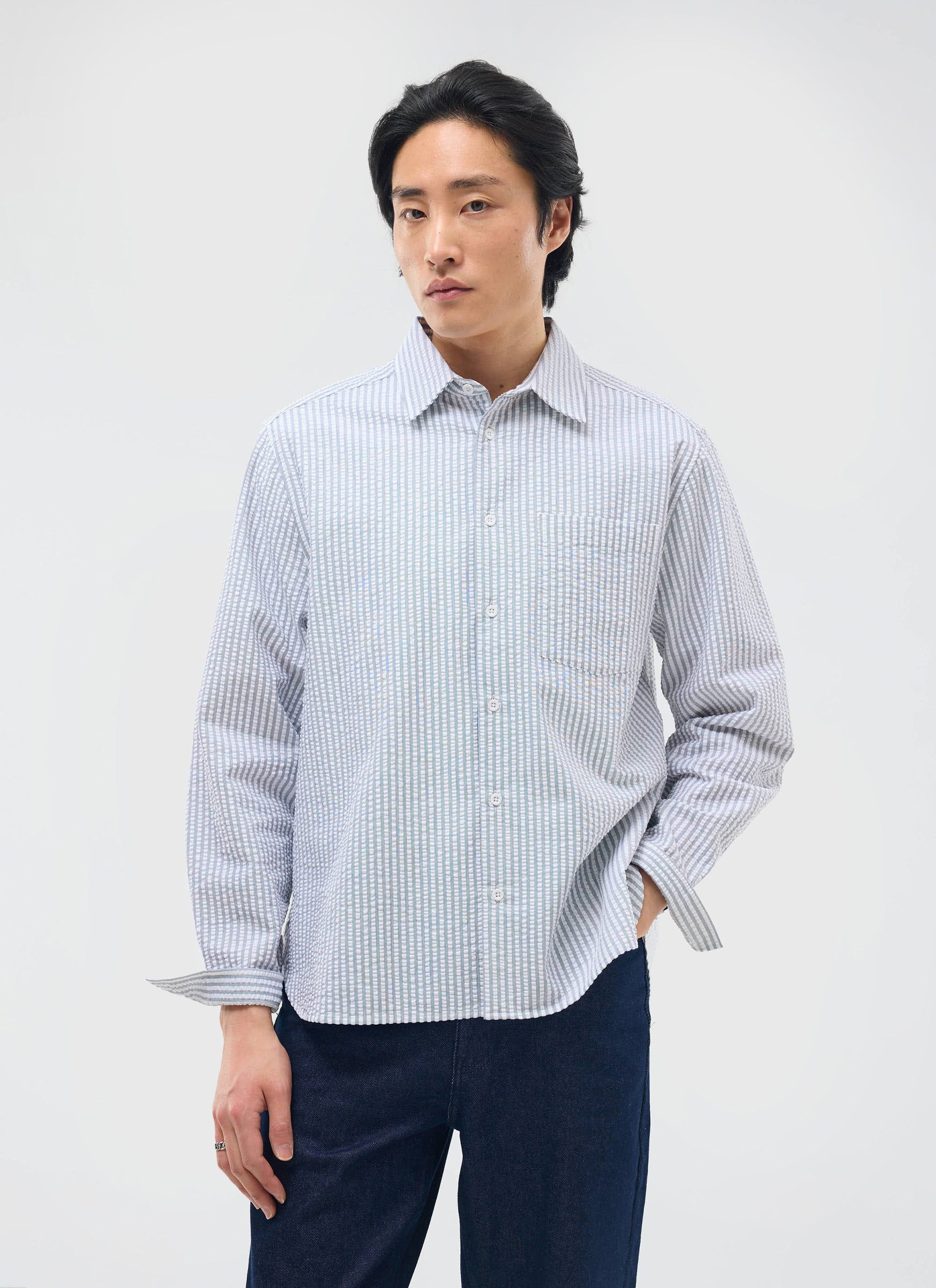A model wears the Percival Seersucker Stripe Pearce Shirt in grey, paired with dark trousers against a white background.