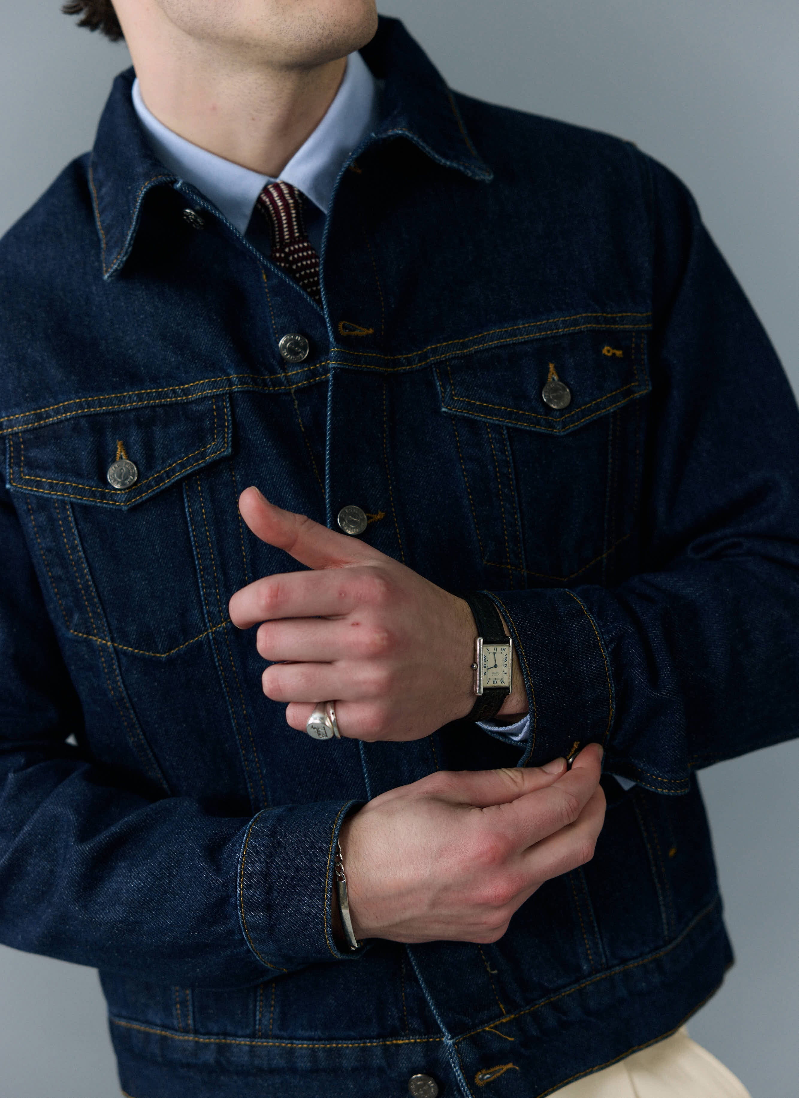 Close-up of a model wearing the Percival Western Trucker Jacket in dark indigo denim over a collared shirt.