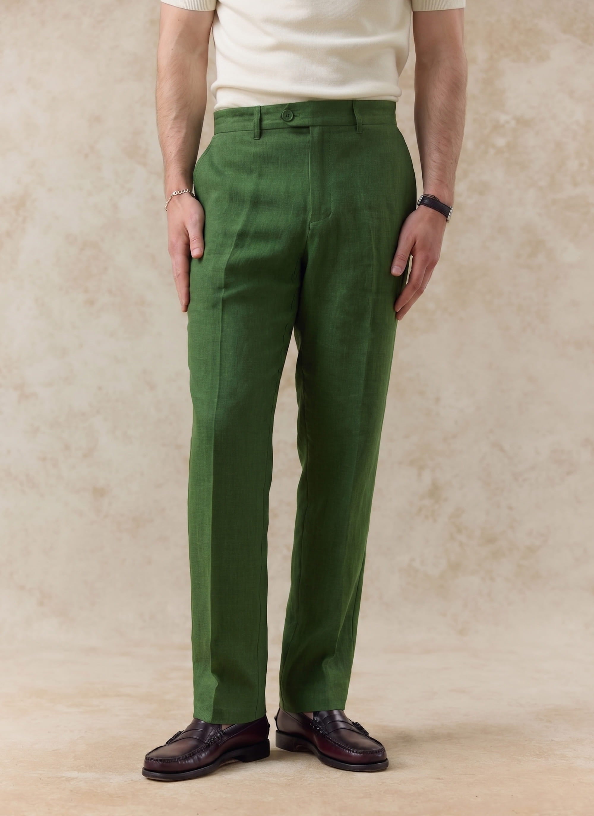 Percival tailored linen trousers in forest green, showing the straight leg fit and styled with brown leather loafers.