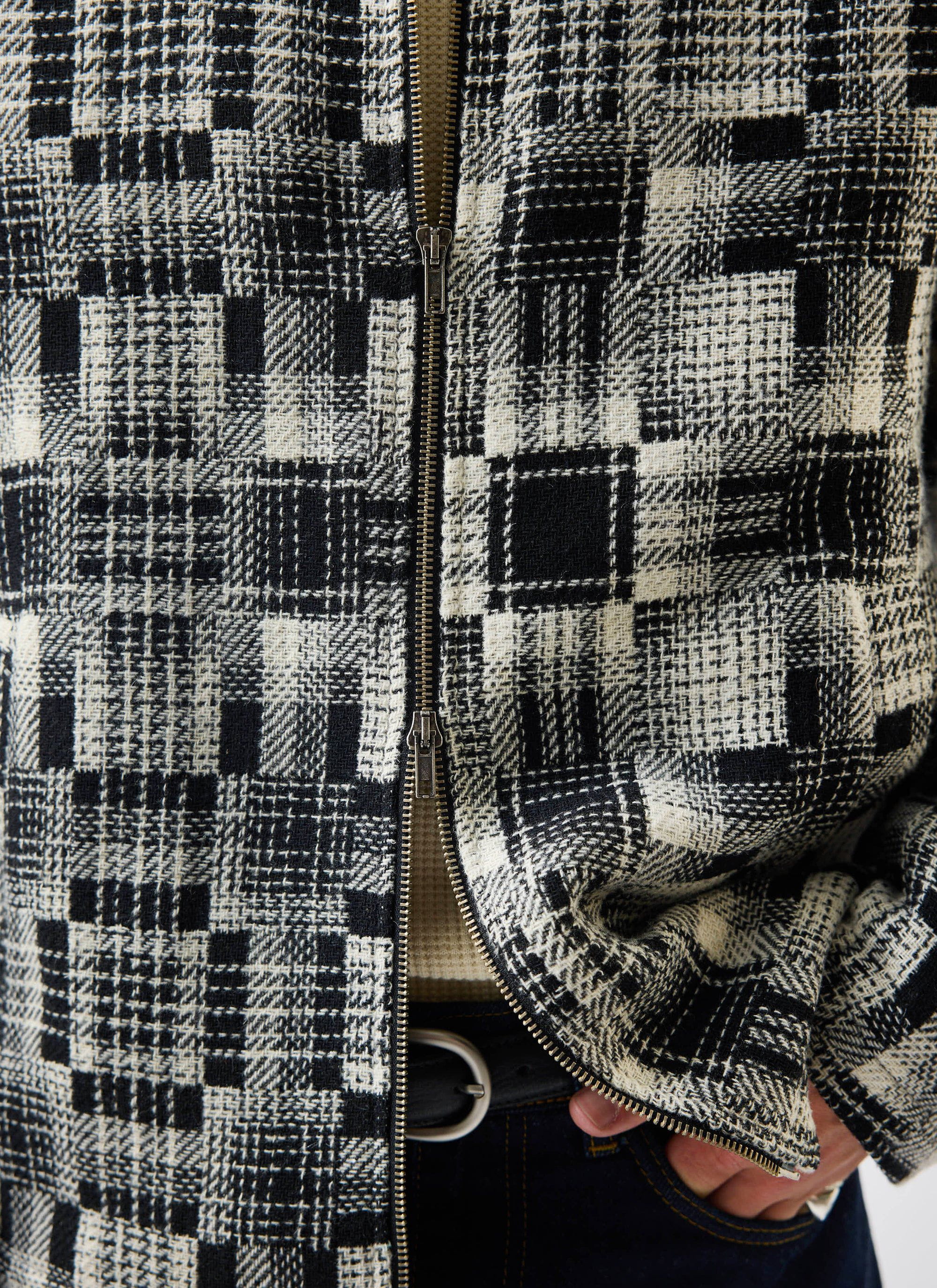 A close-up of the Percival Men's Glossary Patchwork Jacket in grey, showing the textured twill fabric and two-way zip.