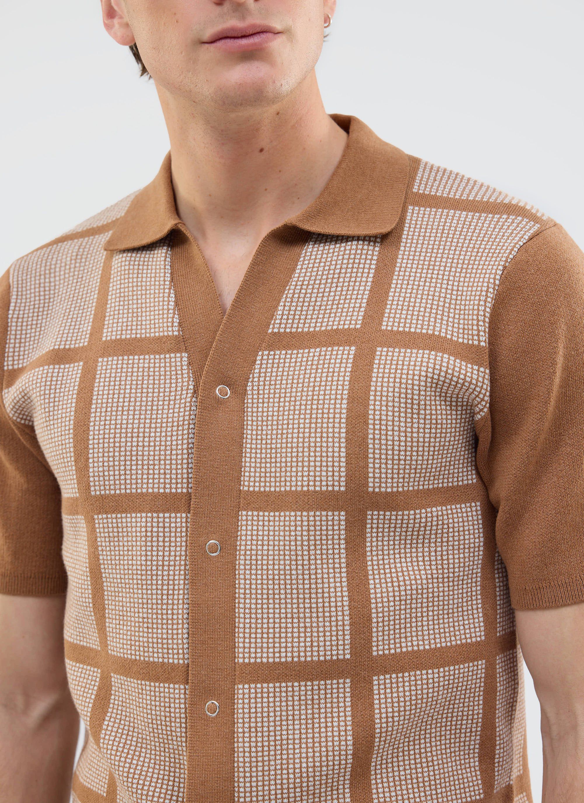 A close-up of a model wearing the tobacco brown Costa Knitted Shirt from Percival, showing its square pattern detail.