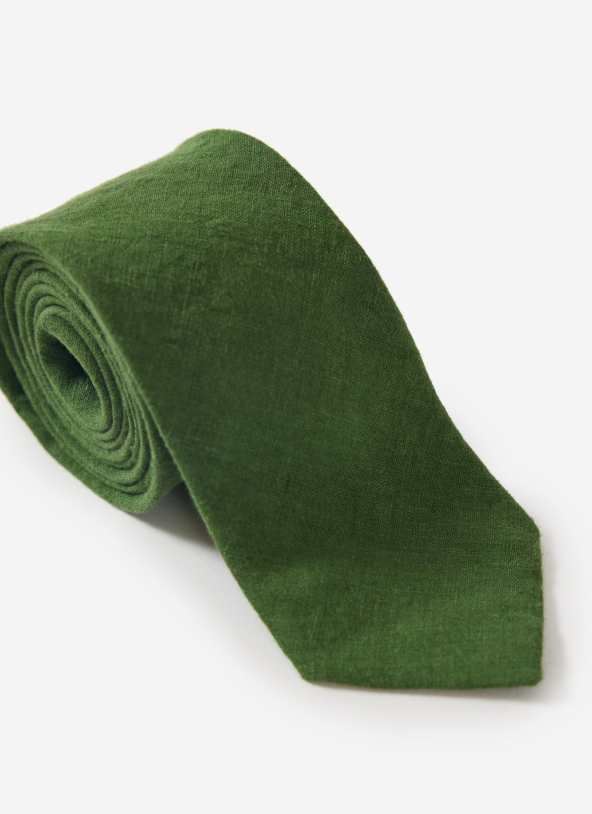 The Percival Linen Tie in forest green, rolled up to display the textured fabric against a clean white background.