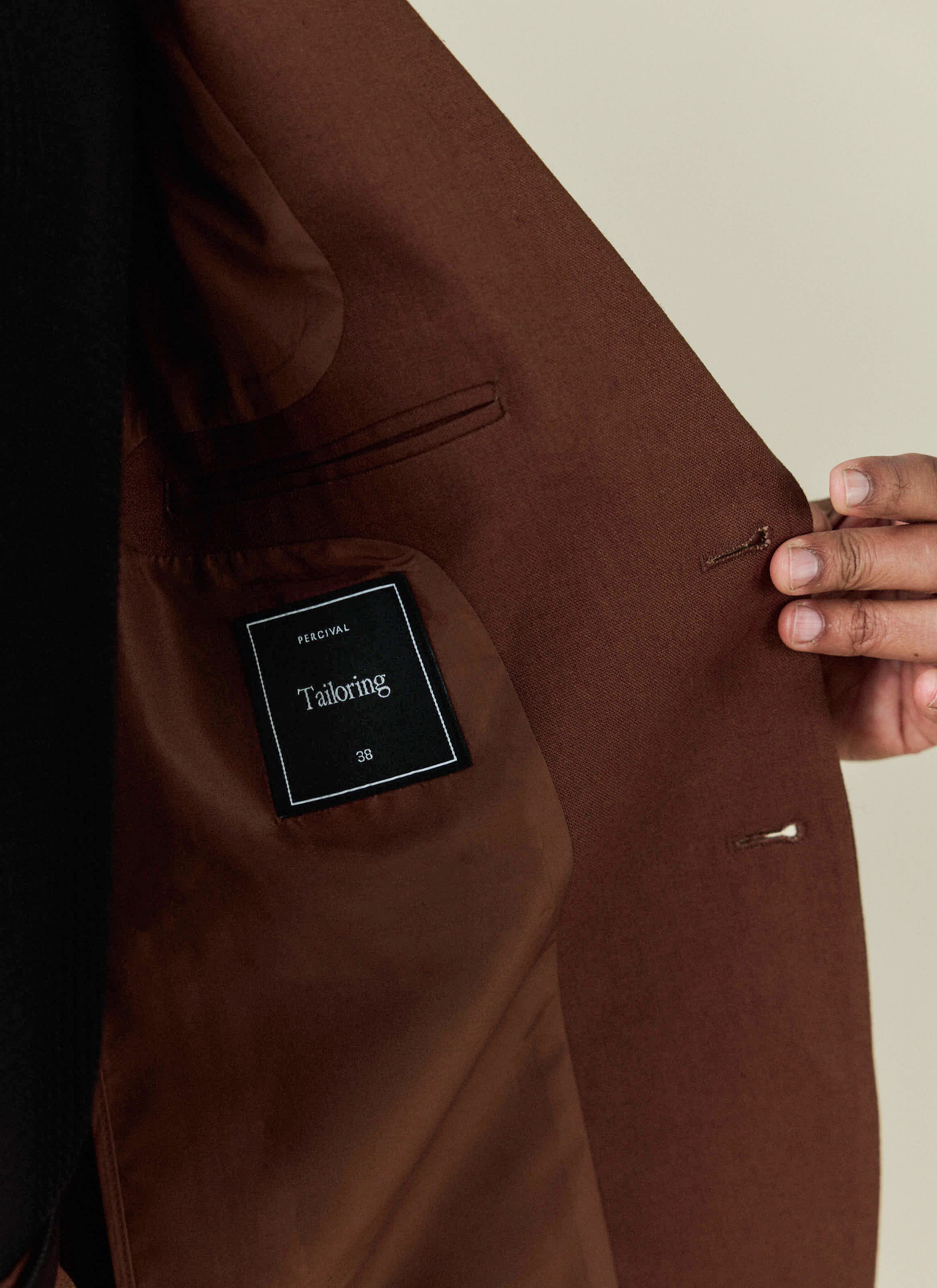 A close-up of the brown Tailored Linen Blazer from Percival, showing the interior pocket and branded tailoring label.