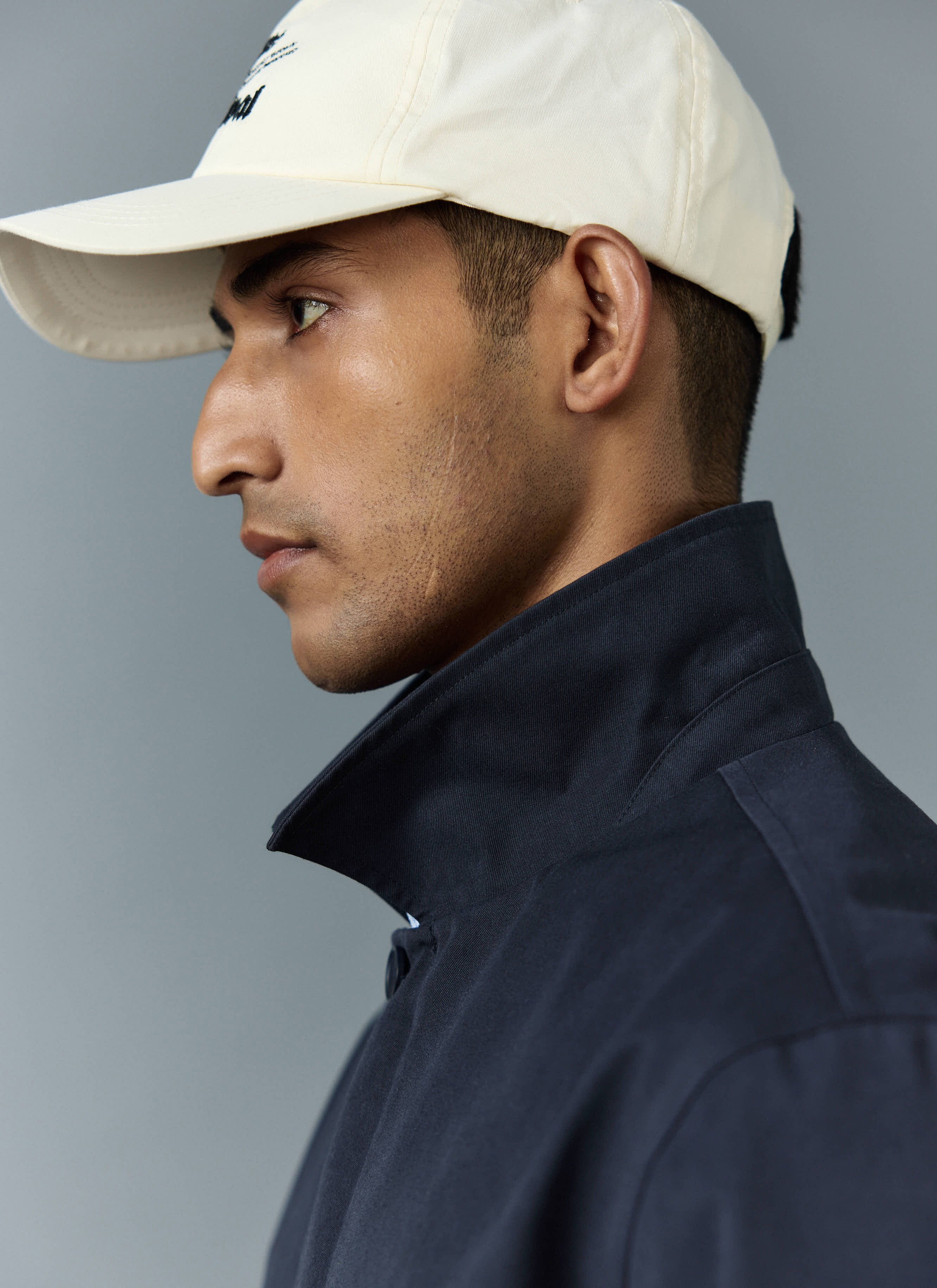 Close up of a model wearing the navy Greyson Long Trench Coat from Percival, showing the detail of the popped collar.