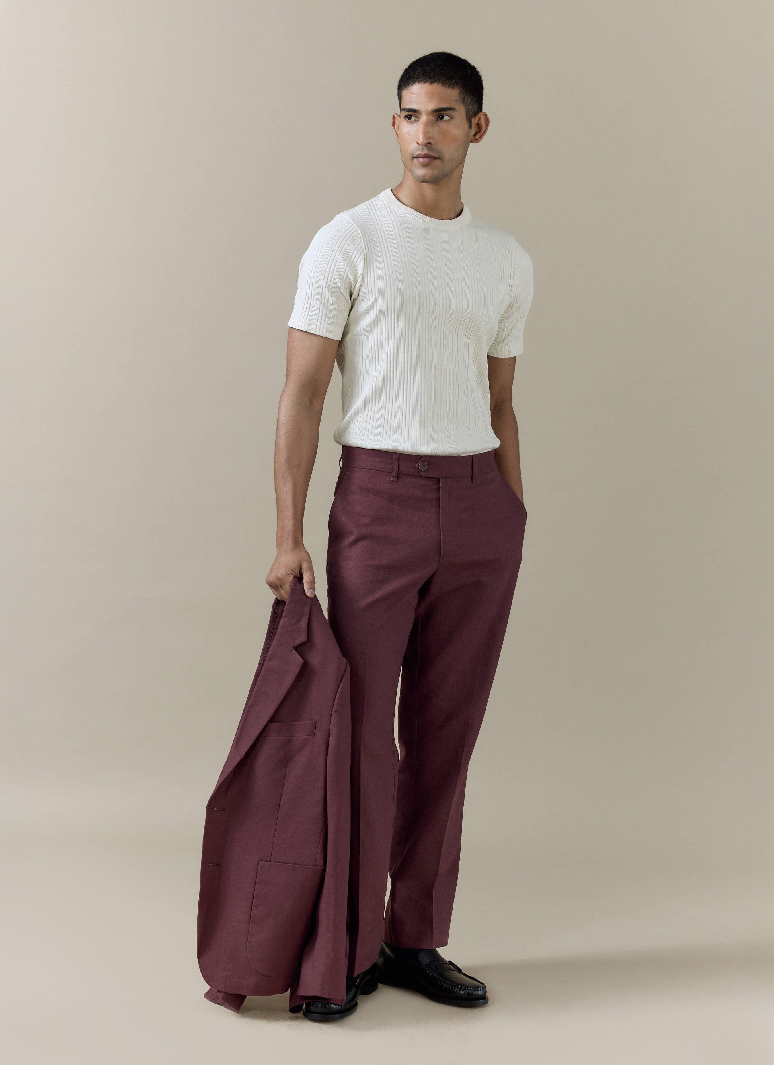 Percival tailored linen trousers in merlot worn with a white ribbed top and matching blazer held by a model.