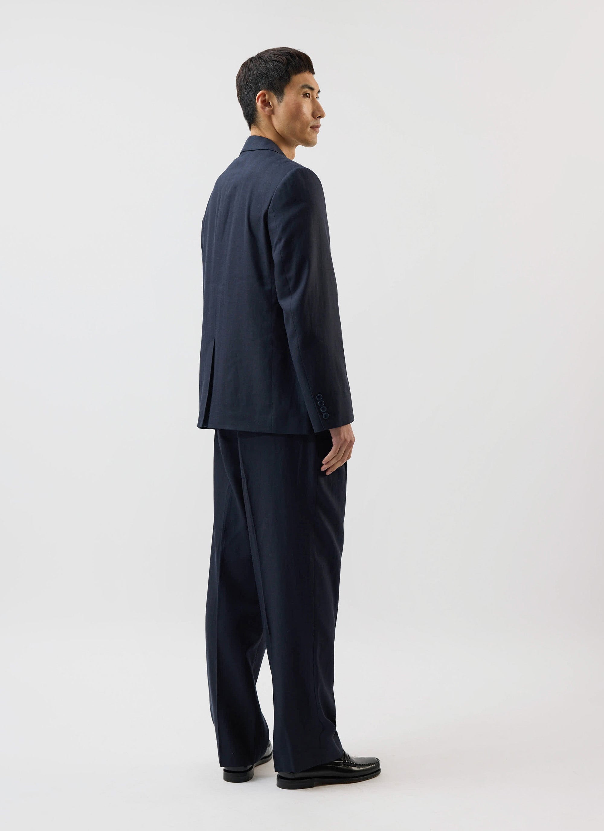 A model seen from the side and back wearing the navy Lyocell Tailored Blazer and matching trousers from Percival.
