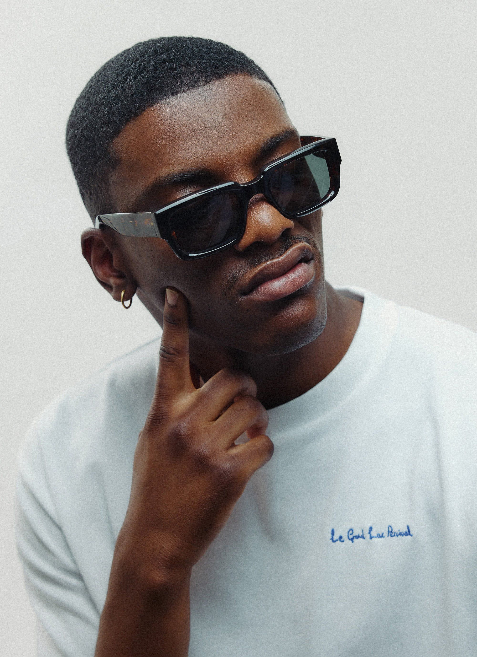 A man models the Percival Demi Brown Tortoise sunglasses, looking thoughtfully to the side against a clean studio background.