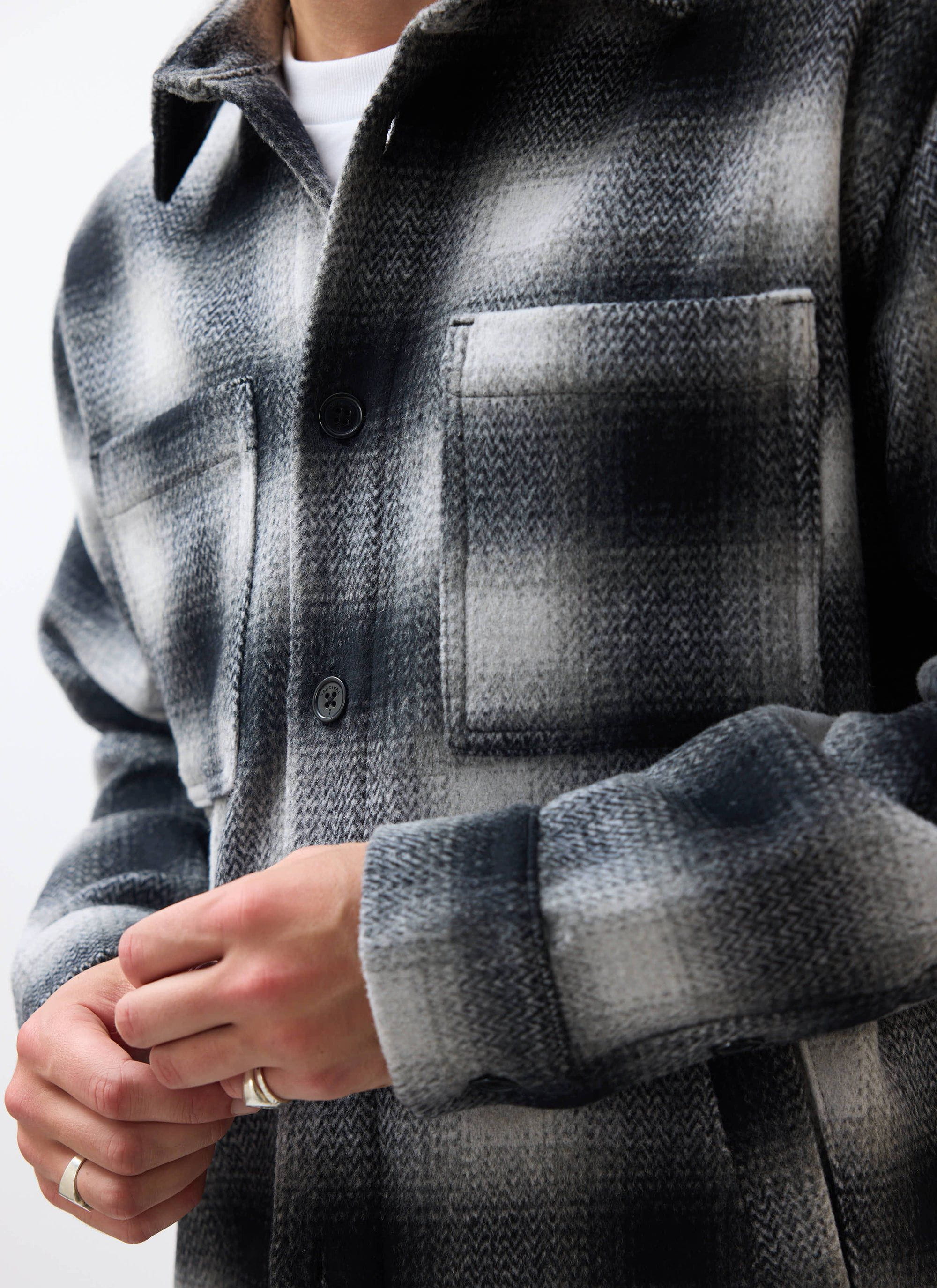 Close up of a model wearing the Percival Check Overshirt in grey, showing the brushed wool blend texture and chest pocket.