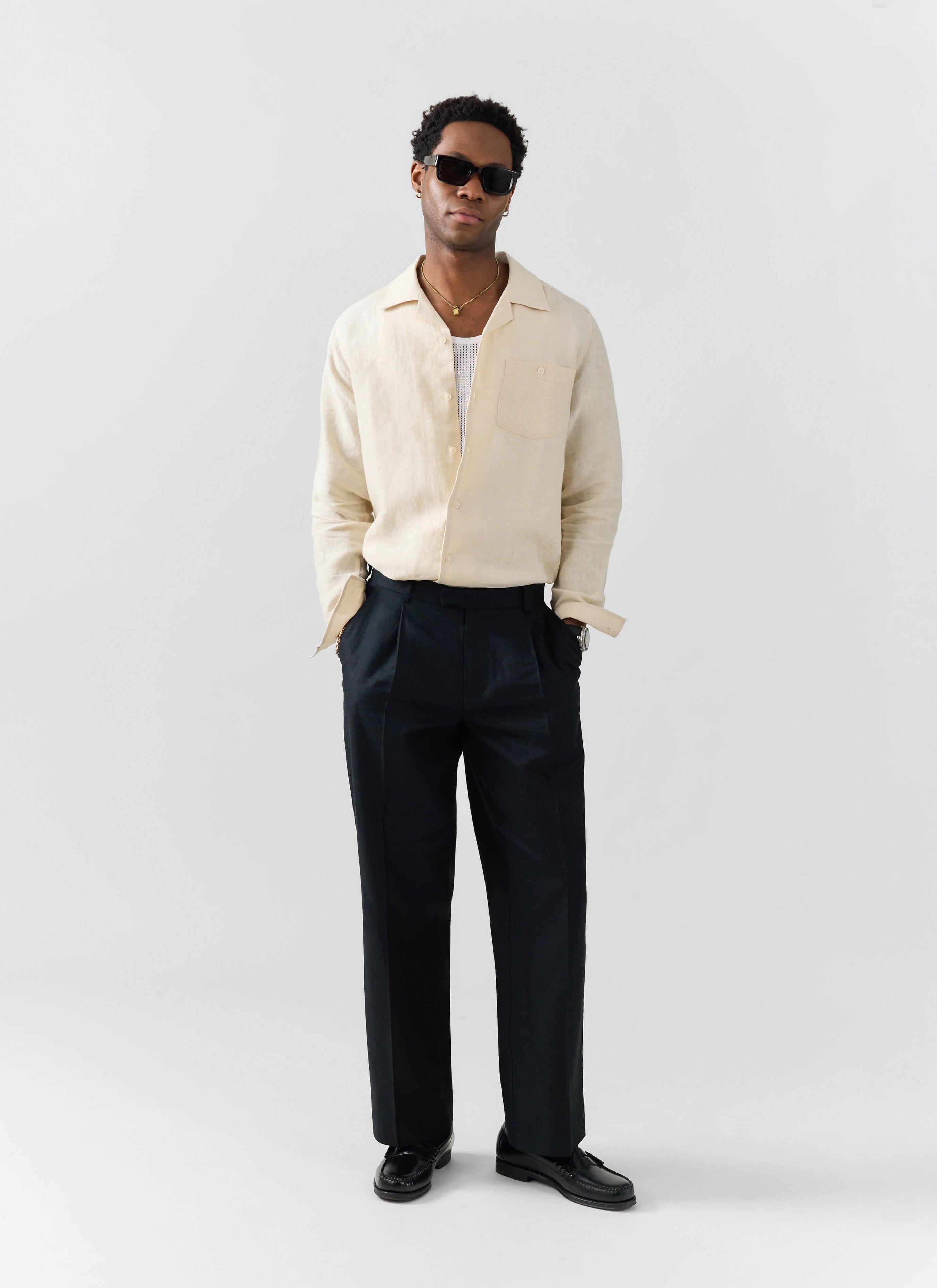 A model wears the Percival cream Long Sleeve Cuban Linen Shirt with black trousers and sunglasses.
