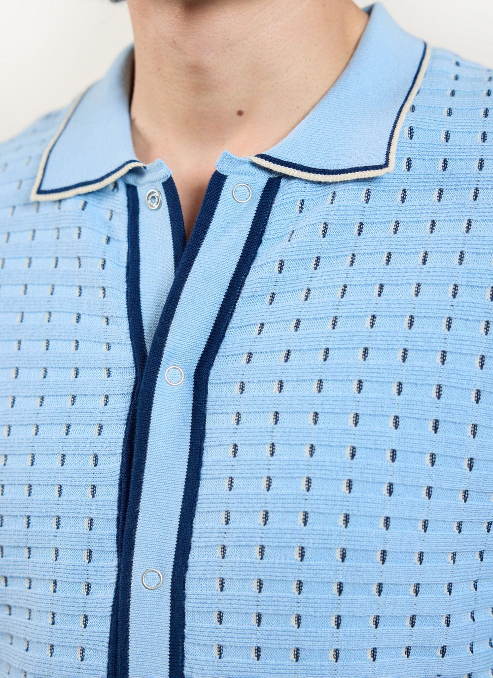 Close up of the Percival blue broken stripe knitted shirt with collar and silver poppers.
