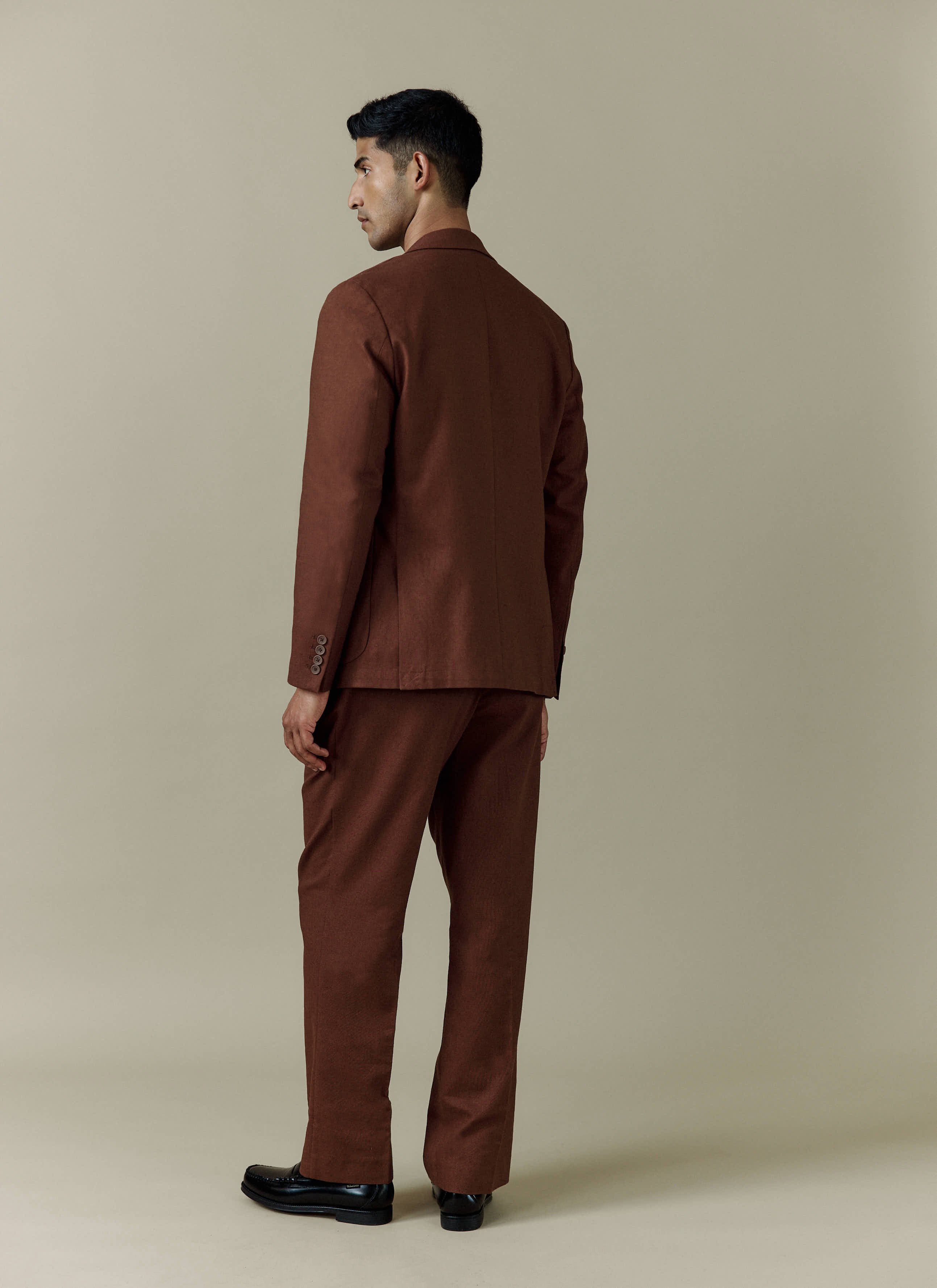 Back view of a model wearing the brown Tailored Linen Blazer and matching trousers from Percival.