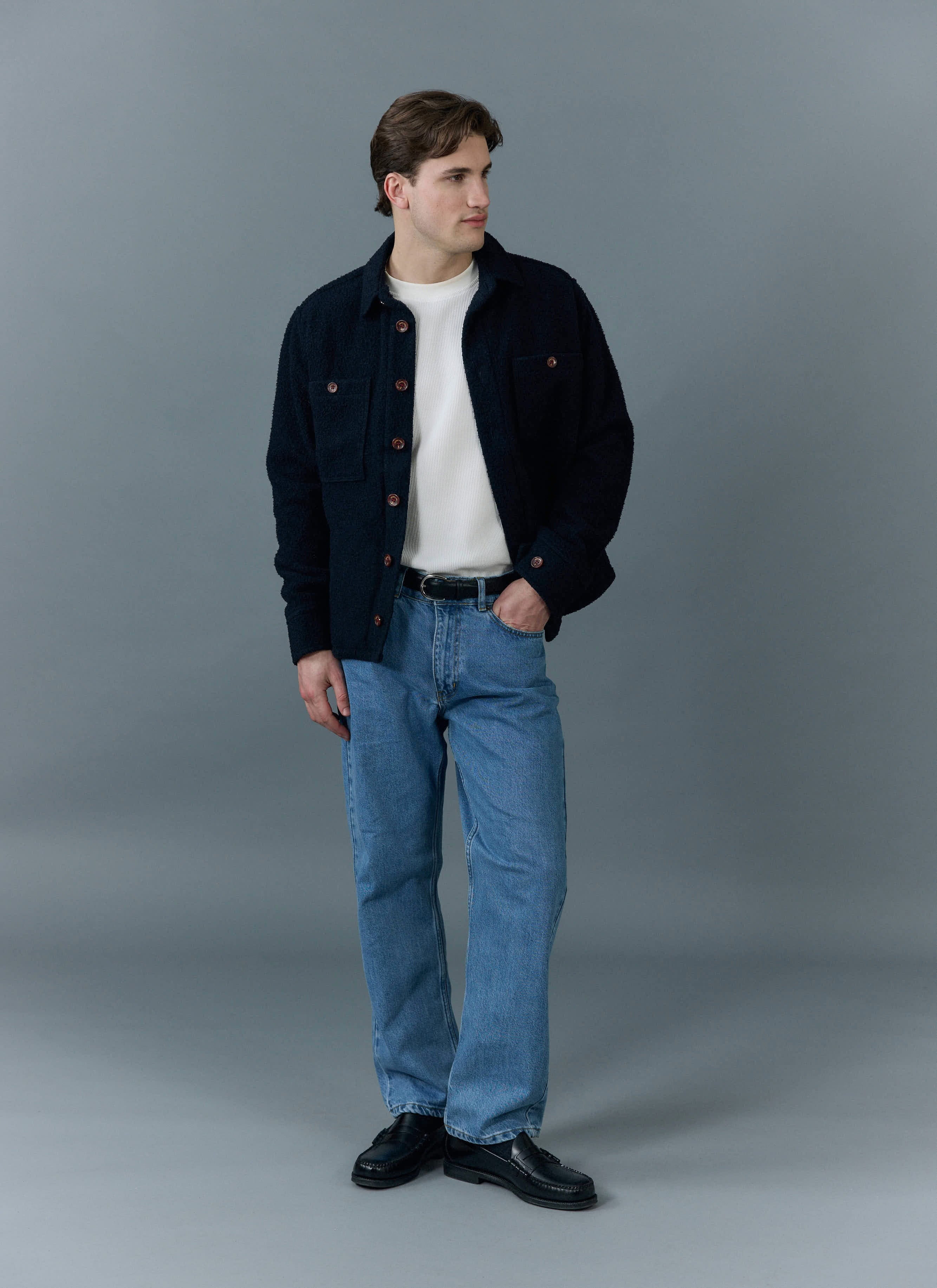 A model wears the Percival Blanket Overshirt in navy Casentino wool with a white t-shirt and blue jeans.