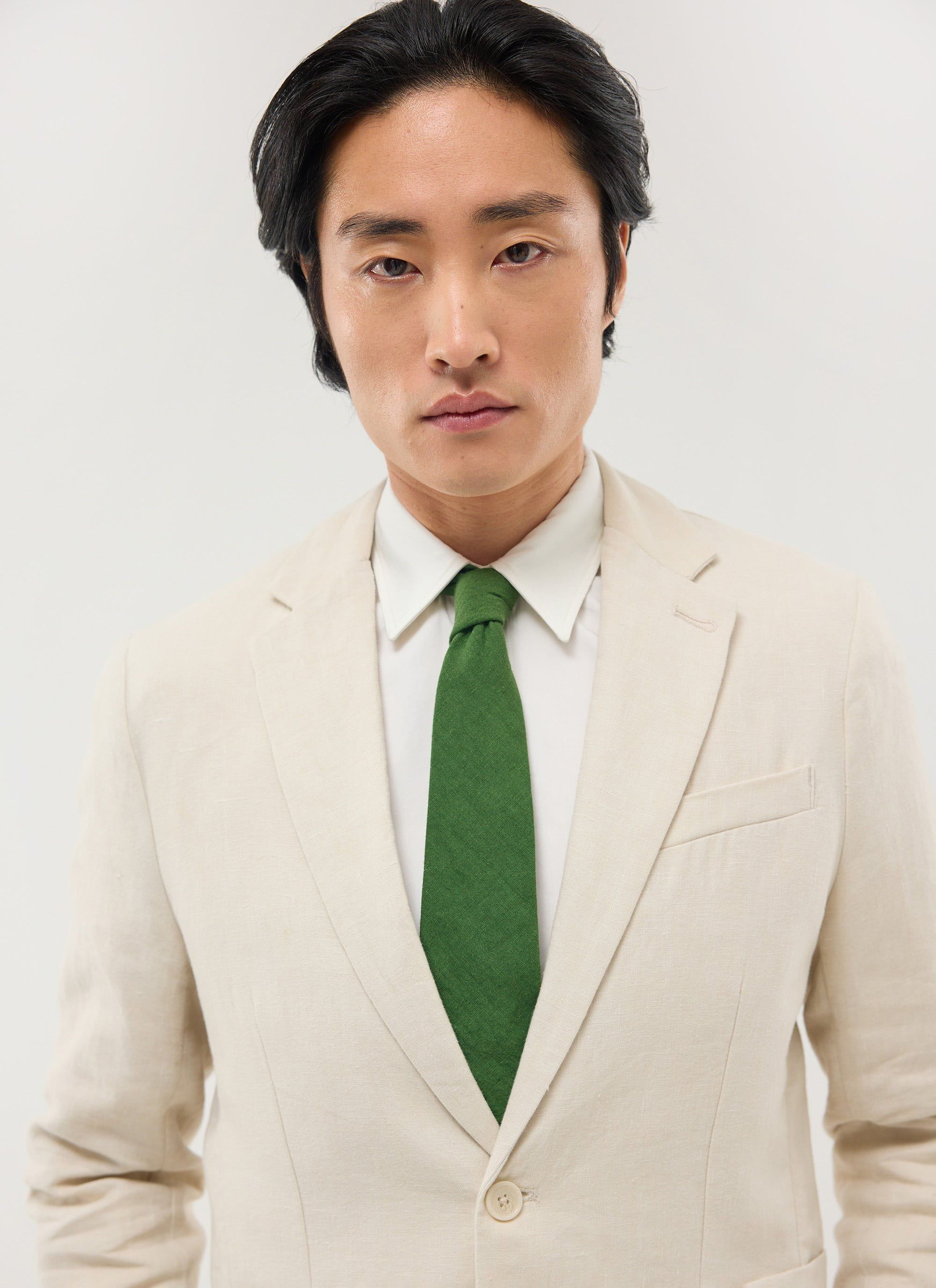 A model wears the Percival Linen Tie in Forest Green, styled with a light-coloured linen suit and a white shirt.