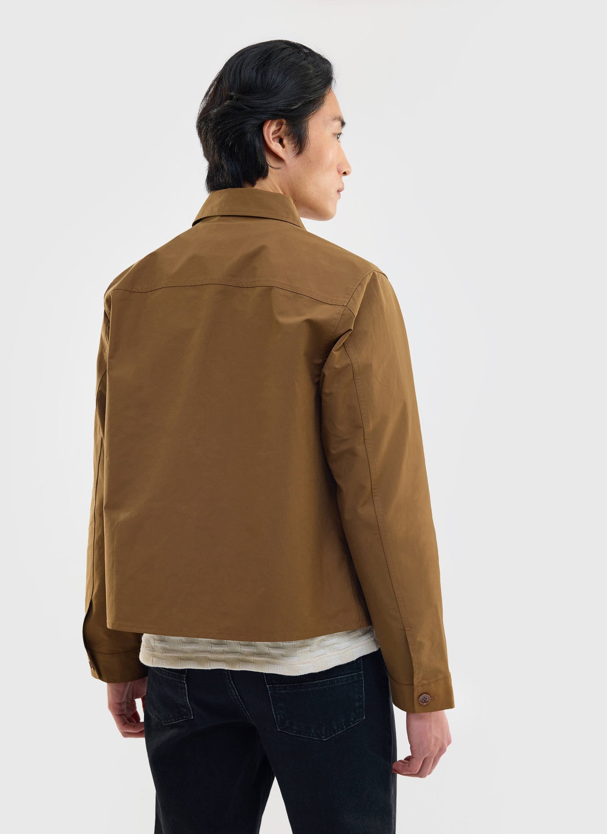 A model, seen from behind, wears the Percival Boxy Cropped Pocket Overshirt in brown, showing off its boxy silhouette.