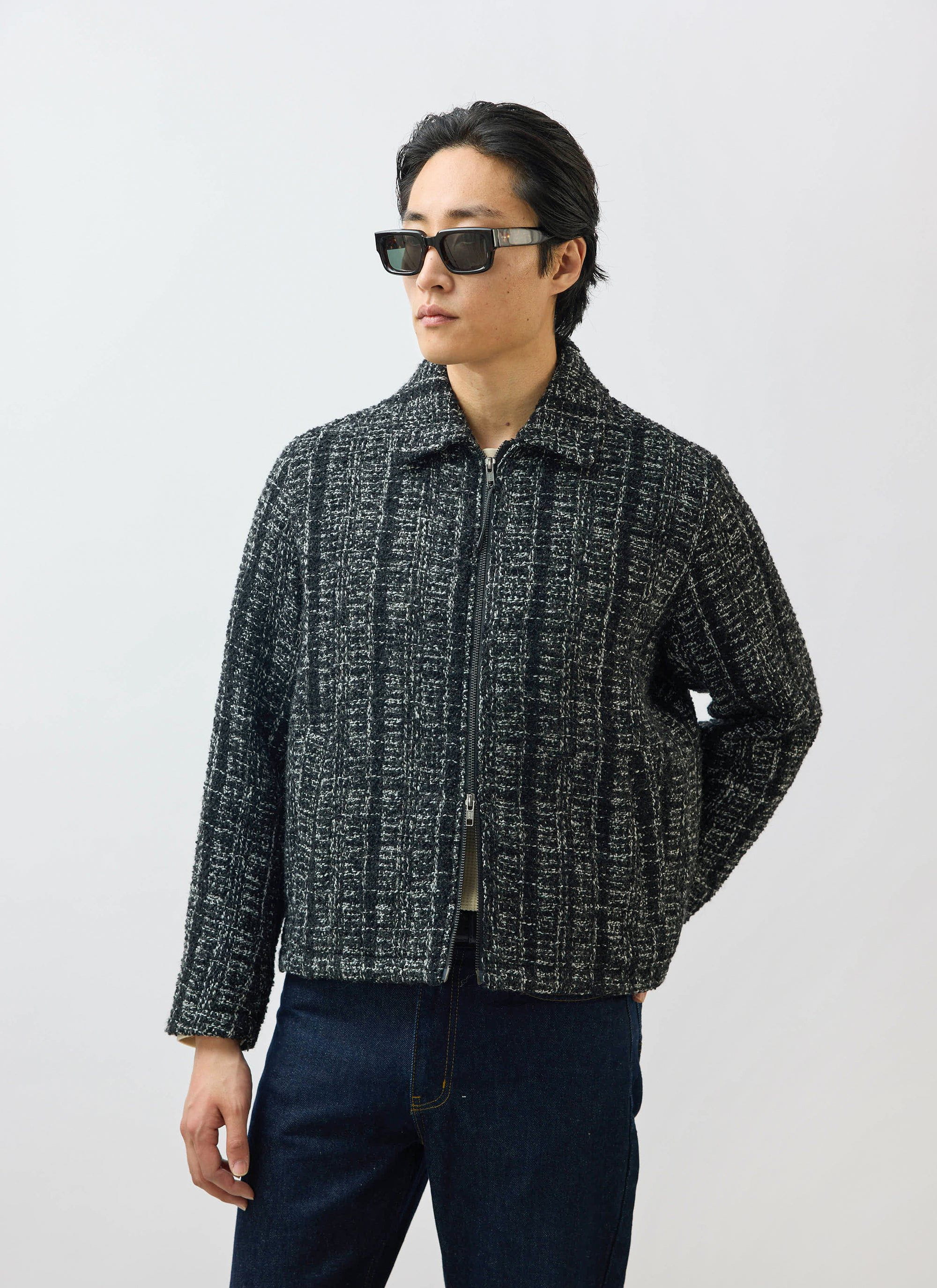 A model wears the Percival Ingegno Zip Wool Boxy Jacket in black bouclé tweed with sunglasses and jeans.
