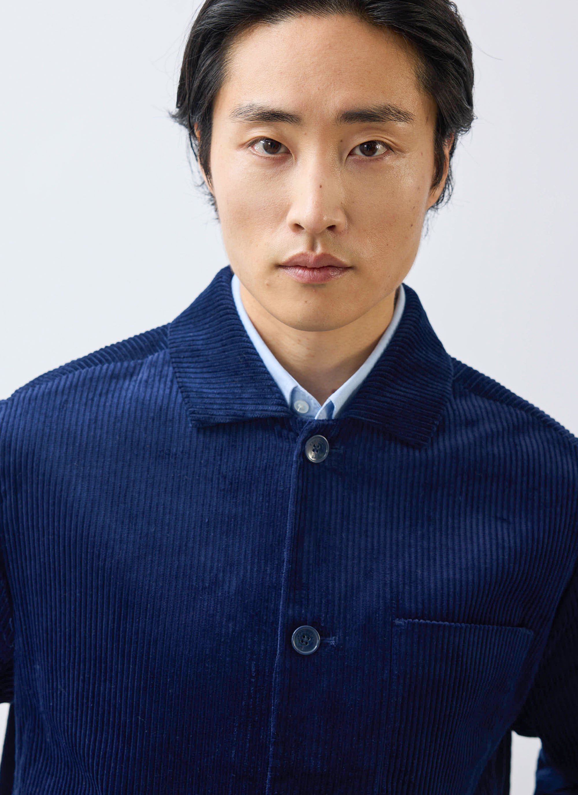 A close-up of a model wearing the Percival Cord Overshirt in navy, showing the corduroy texture and collar detail.