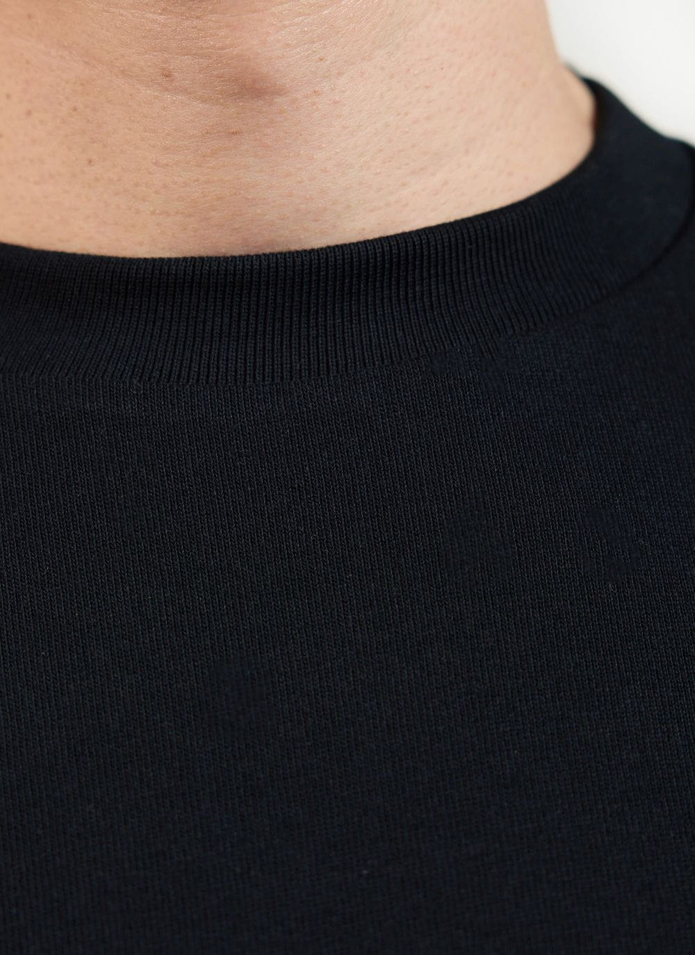 Close up of the ribbed crew neck on a black oversized organic cotton t-shirt by Percival.