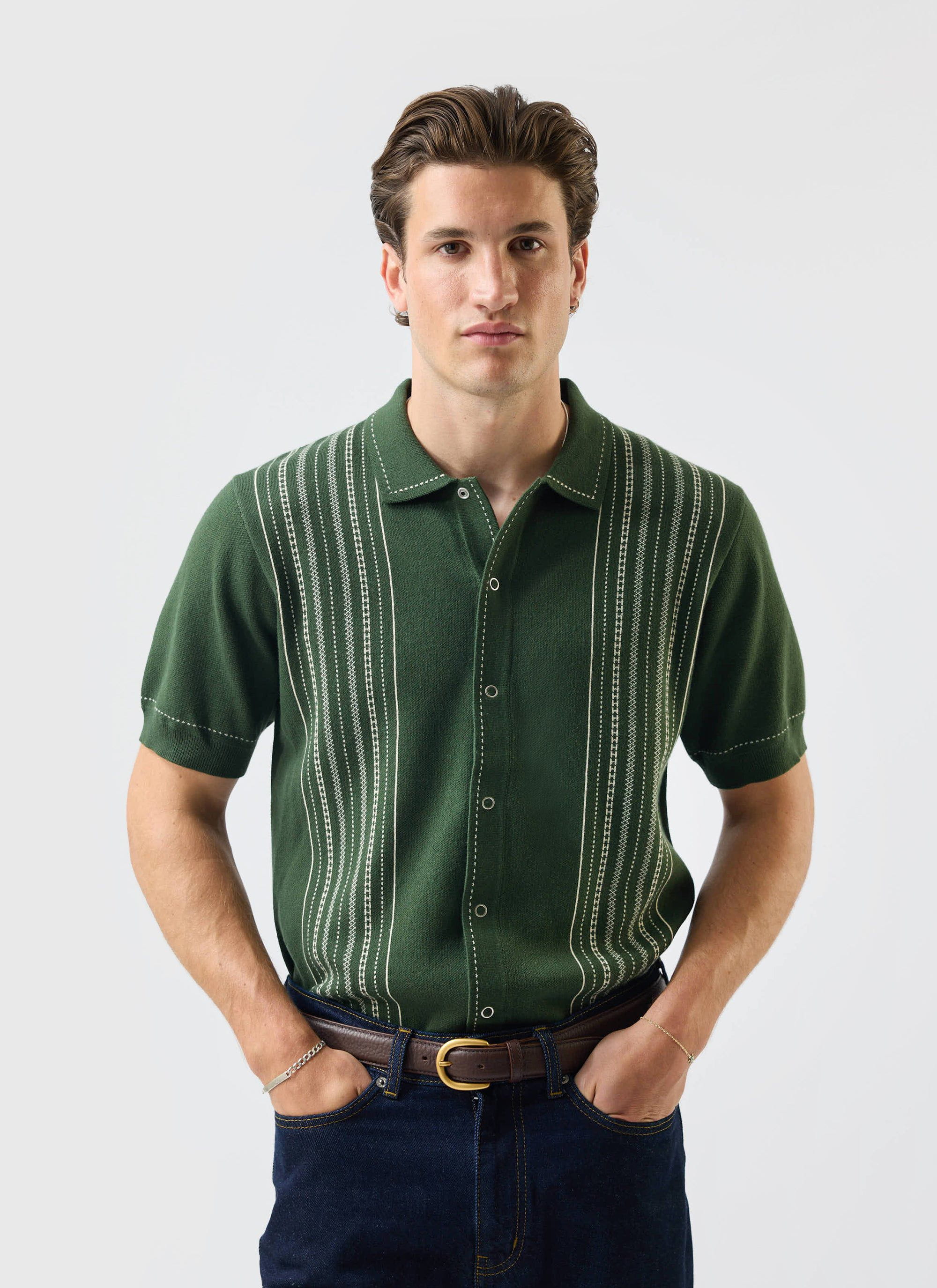 A model wears the Percival Accolades Knitted Short Sleeve Shirt in forest green with dark jeans against a white background.