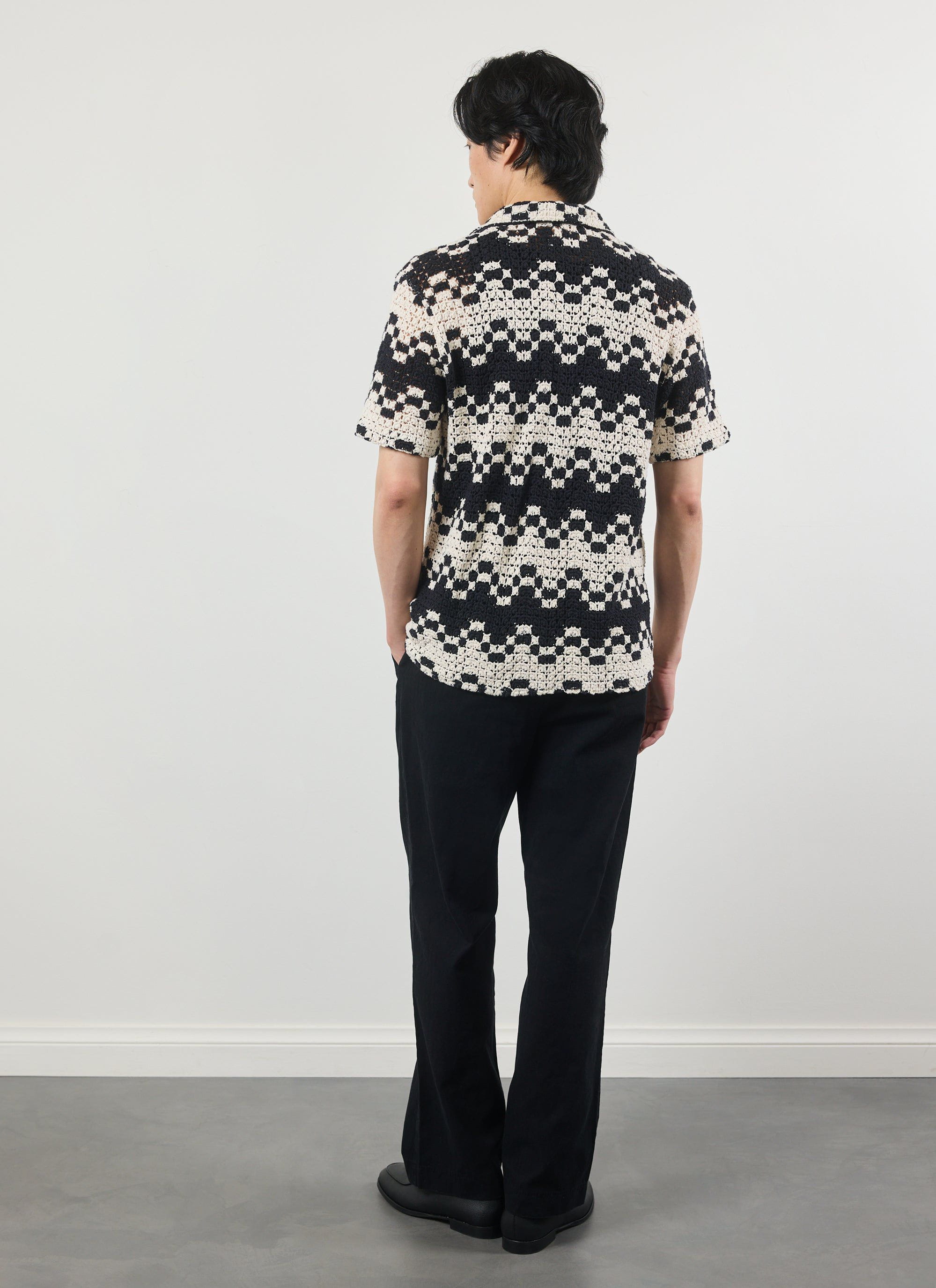 A model seen from behind wearing the Percival Naples Crochet Cuban Shirt, showing the intricate black and ecru pattern.