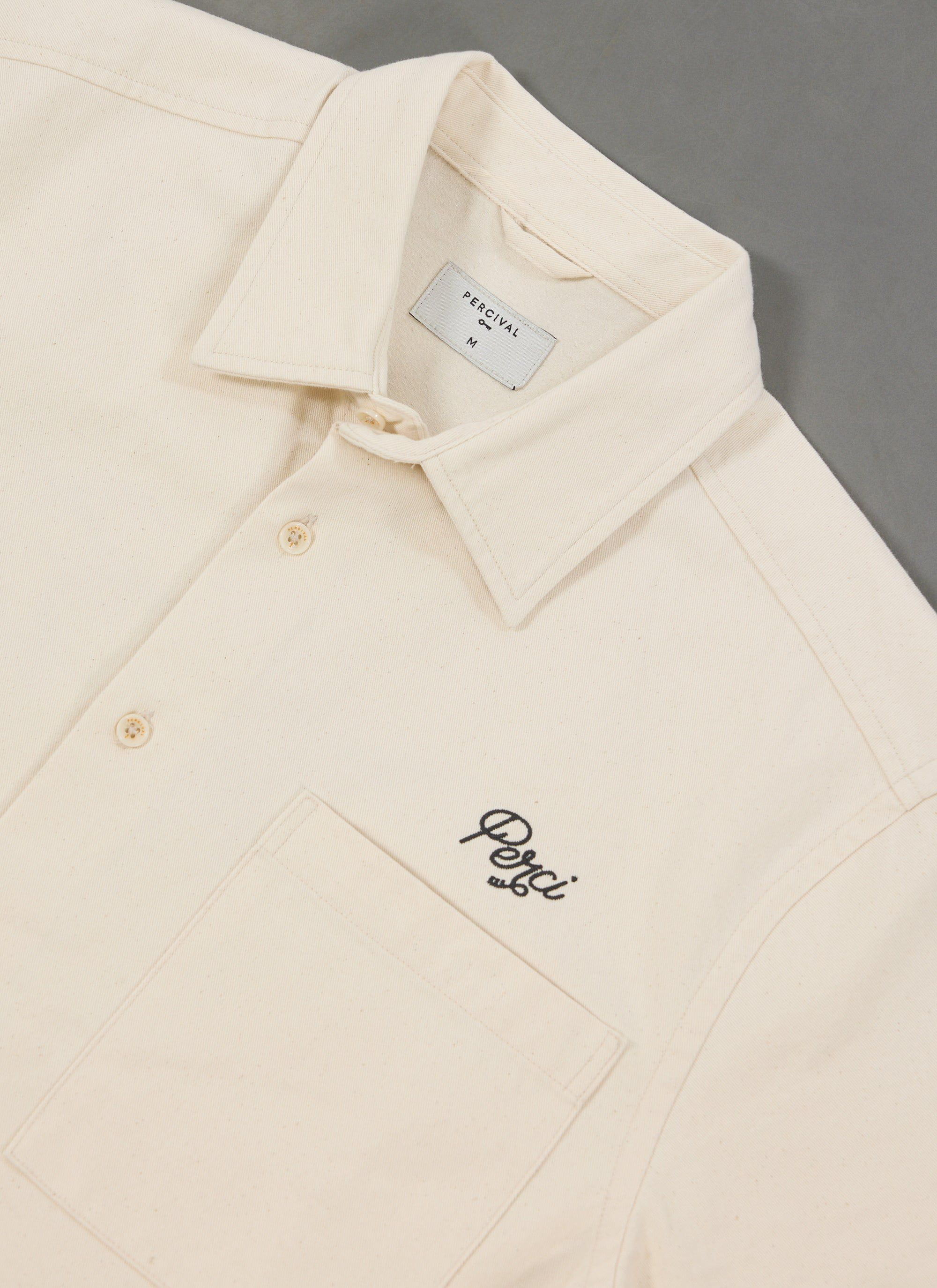 A close-up of the Percival Olive Embroidered Cropped Shirt in off-white, showing the 'Perci' script embroidery on the chest.