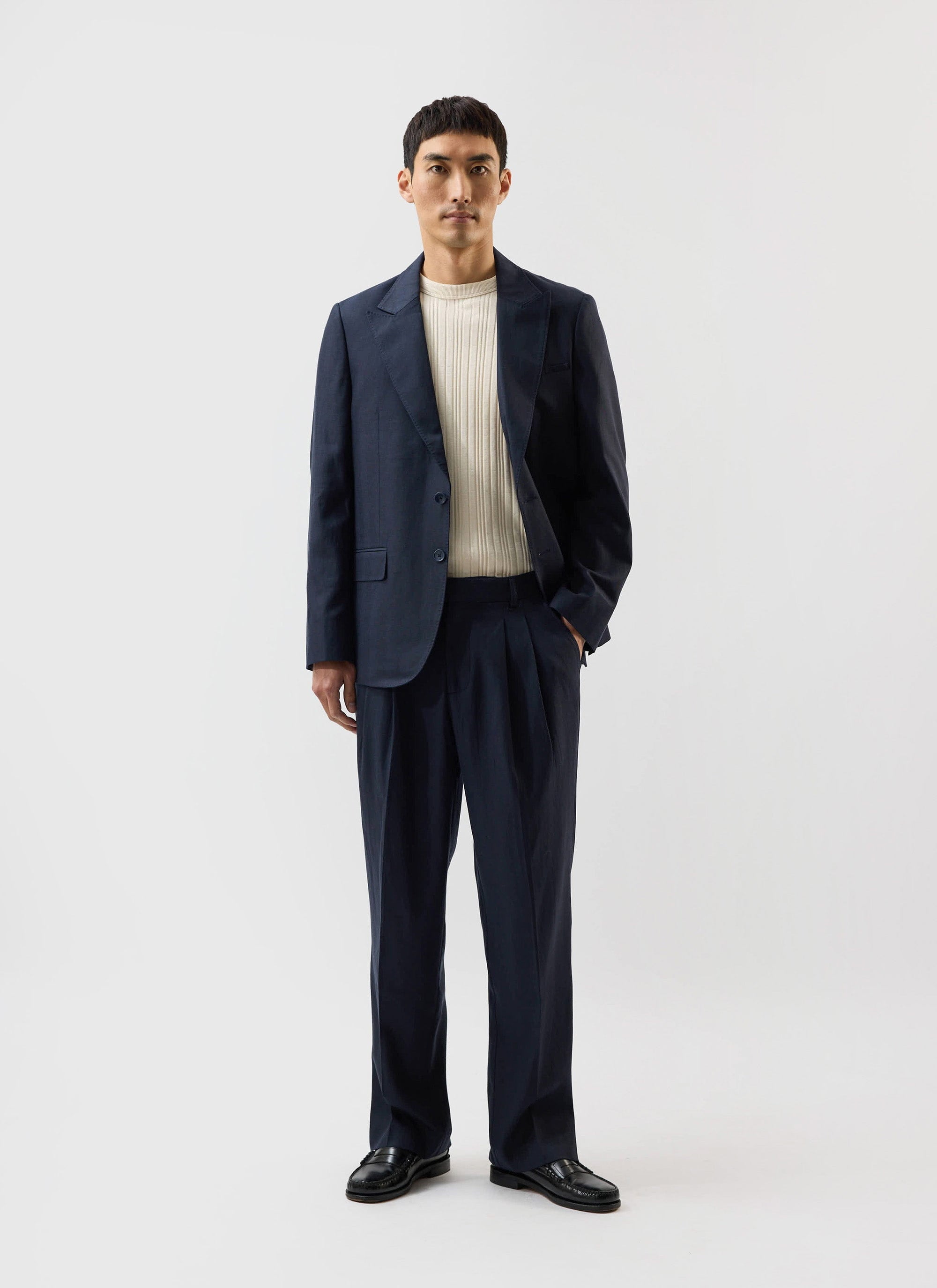 A model wears the navy Lyocell Tailored Blazer by Percival x Warren, paired with matching trousers and a cream knit.
