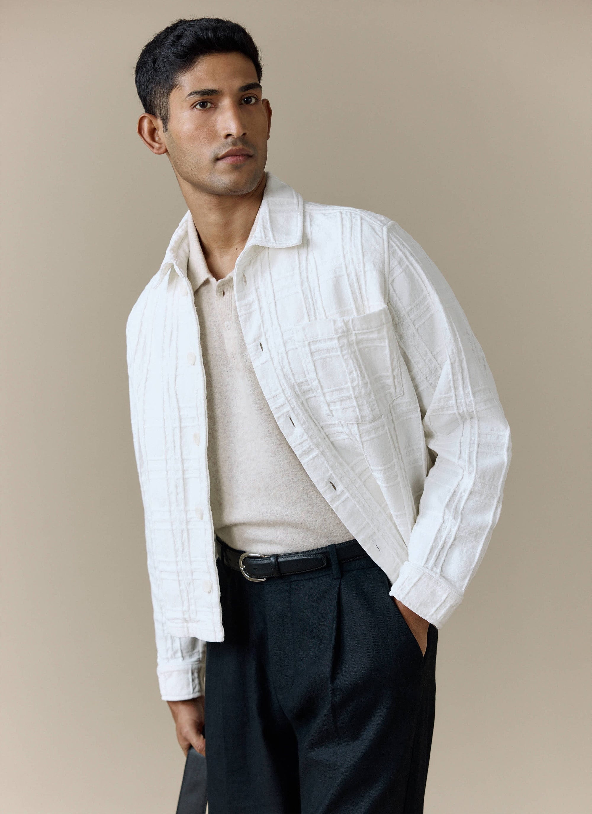 A model wears the ecru Canyon Heavyweight Overshirt from Percival, layered over a polo shirt and dark trousers.