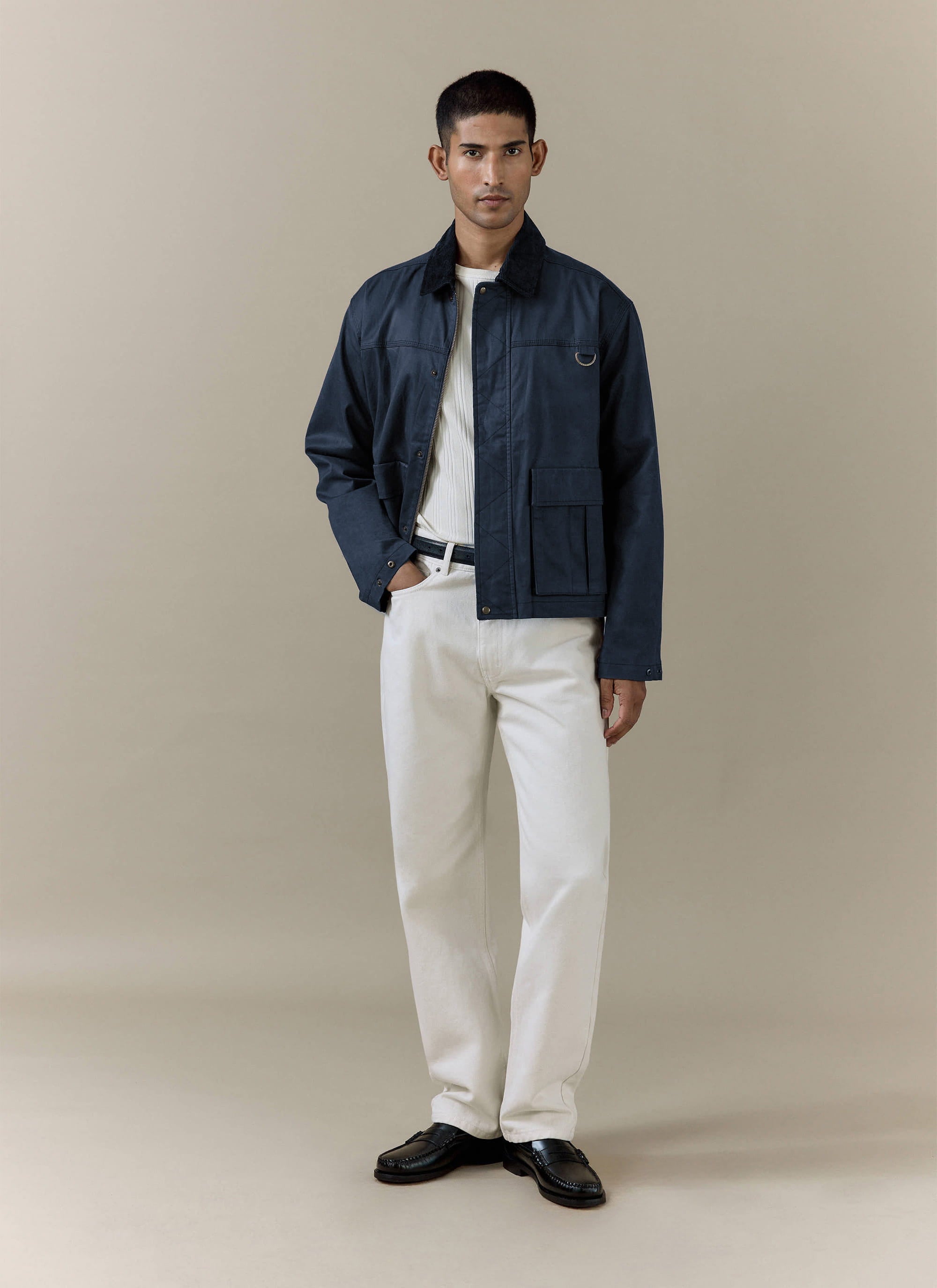 Navy blue Percival Wax Zip Jacket in waxed cotton, styled with white trousers and loafers in a studio shot.