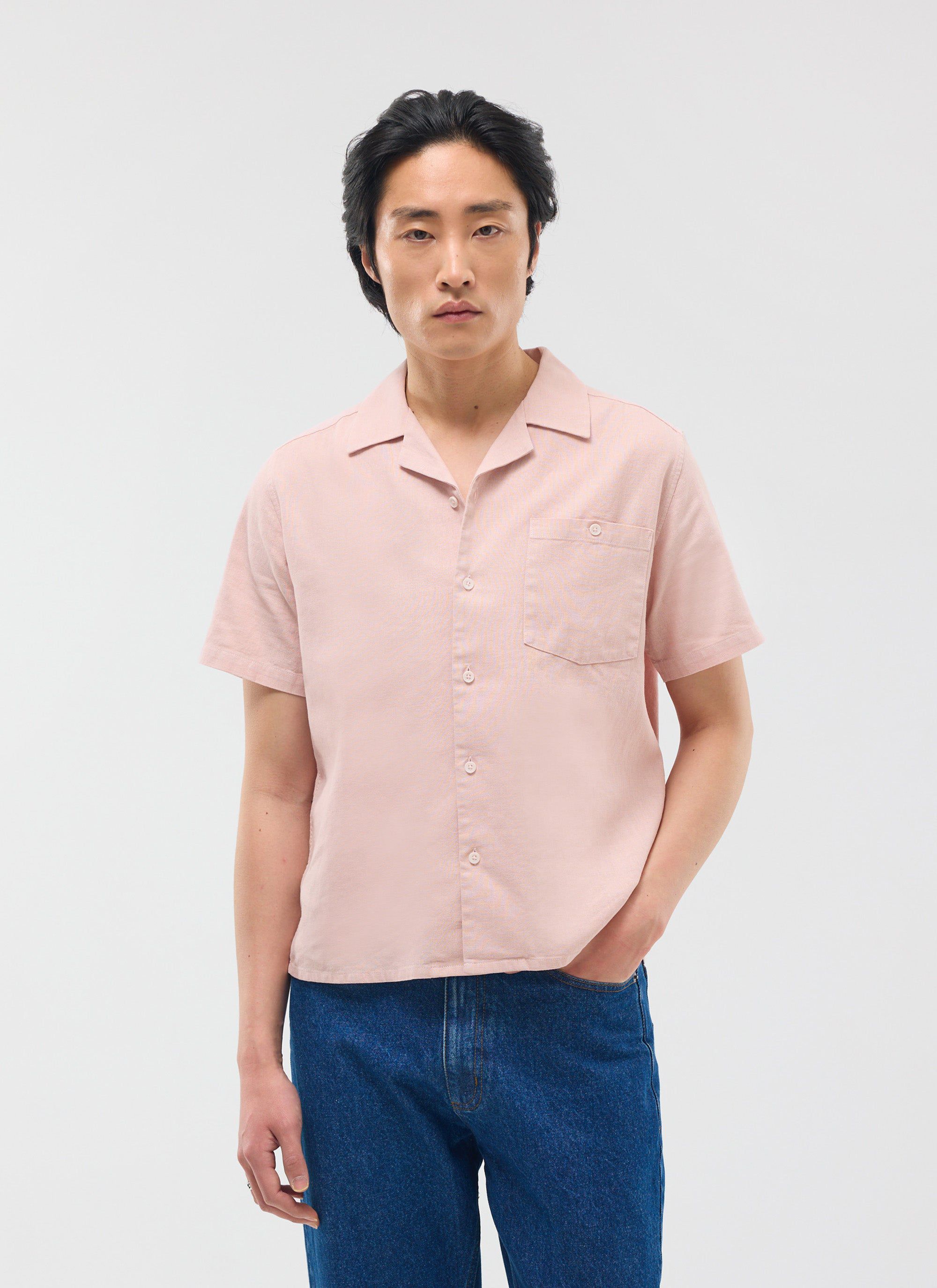 A model wears the Percival Short Sleeve Cuban Shirt in dusty pink linen, styled with blue jeans against a white background.