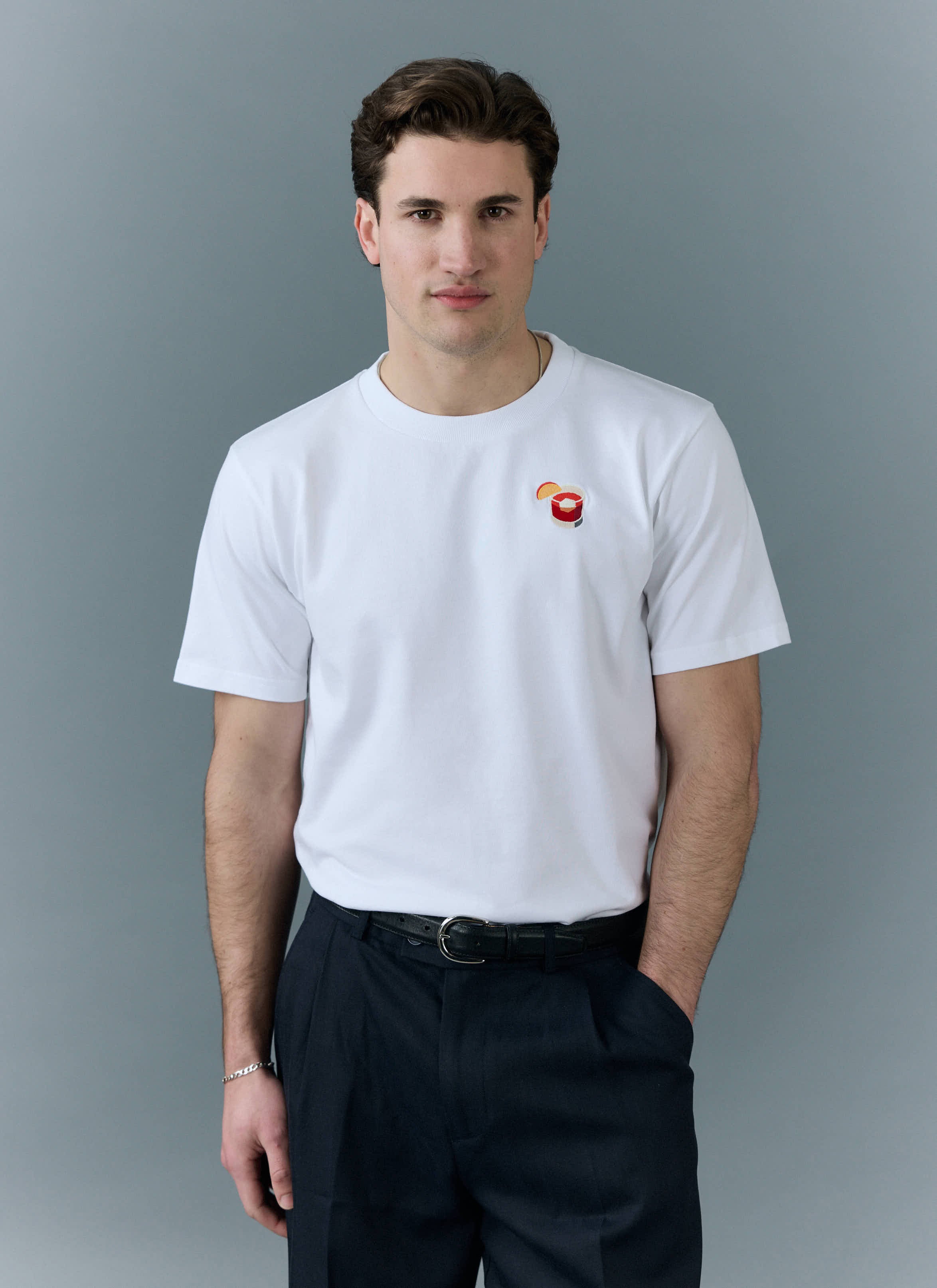 A man wearing the white Negroni T Shirt from Percival, with its signature embroidered cocktail on the chest.