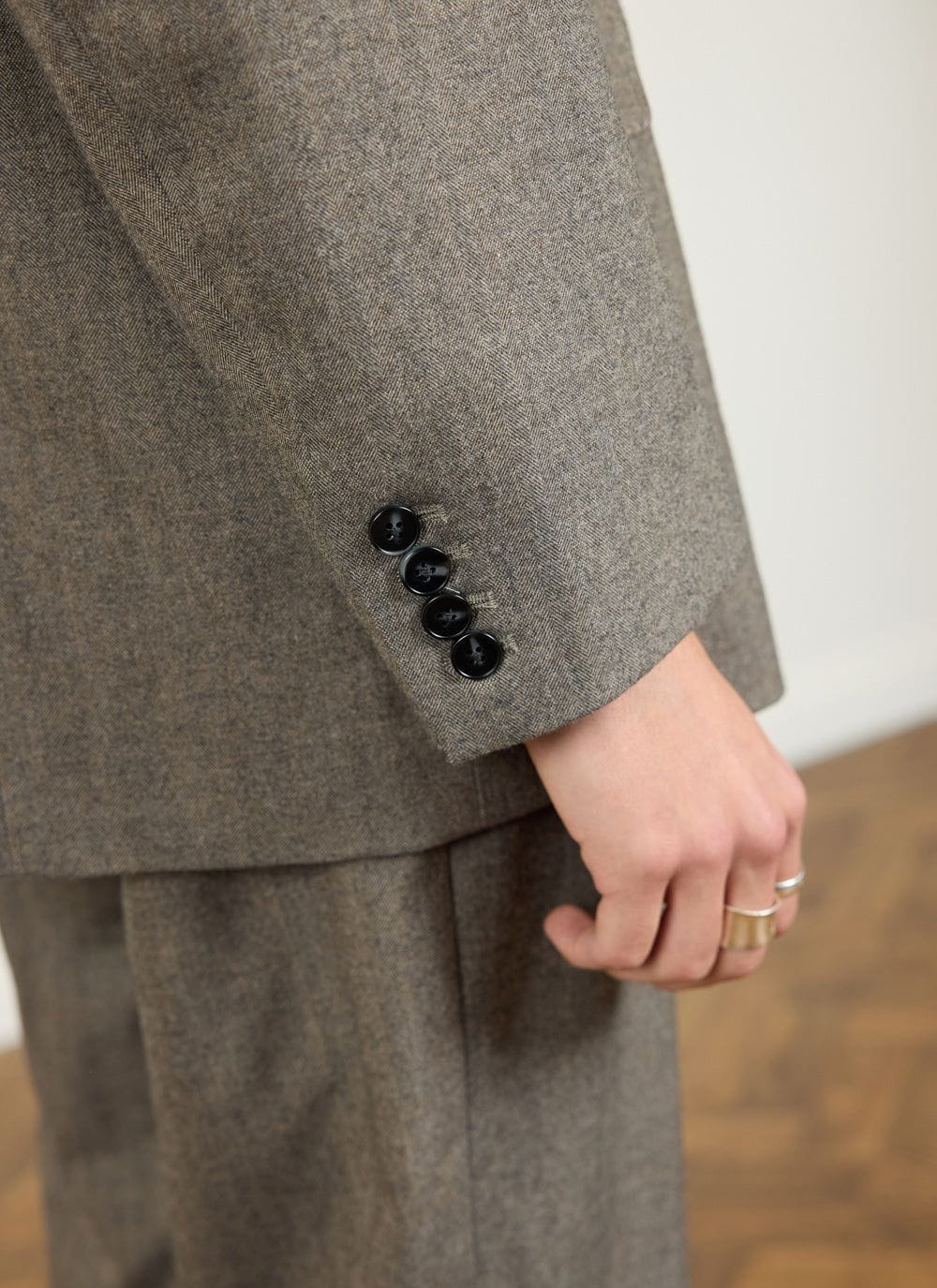 Close up of the Percival grey herringbone blazer sleeve and cuff with four black buttons.