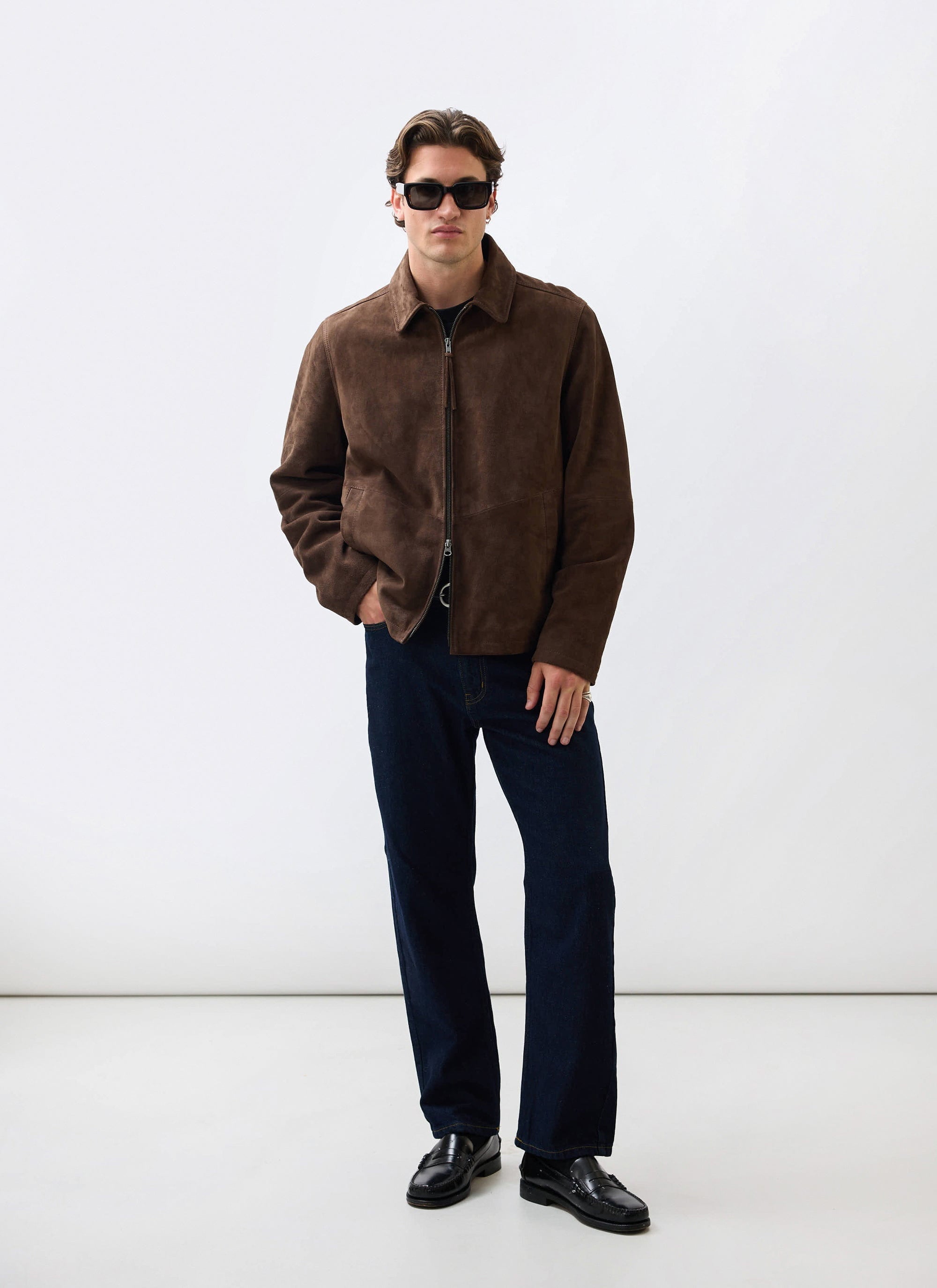 A model wears the Percival Prologue Soft Suede Jacket in Espresso Brown, styled with dark jeans and sunglasses.