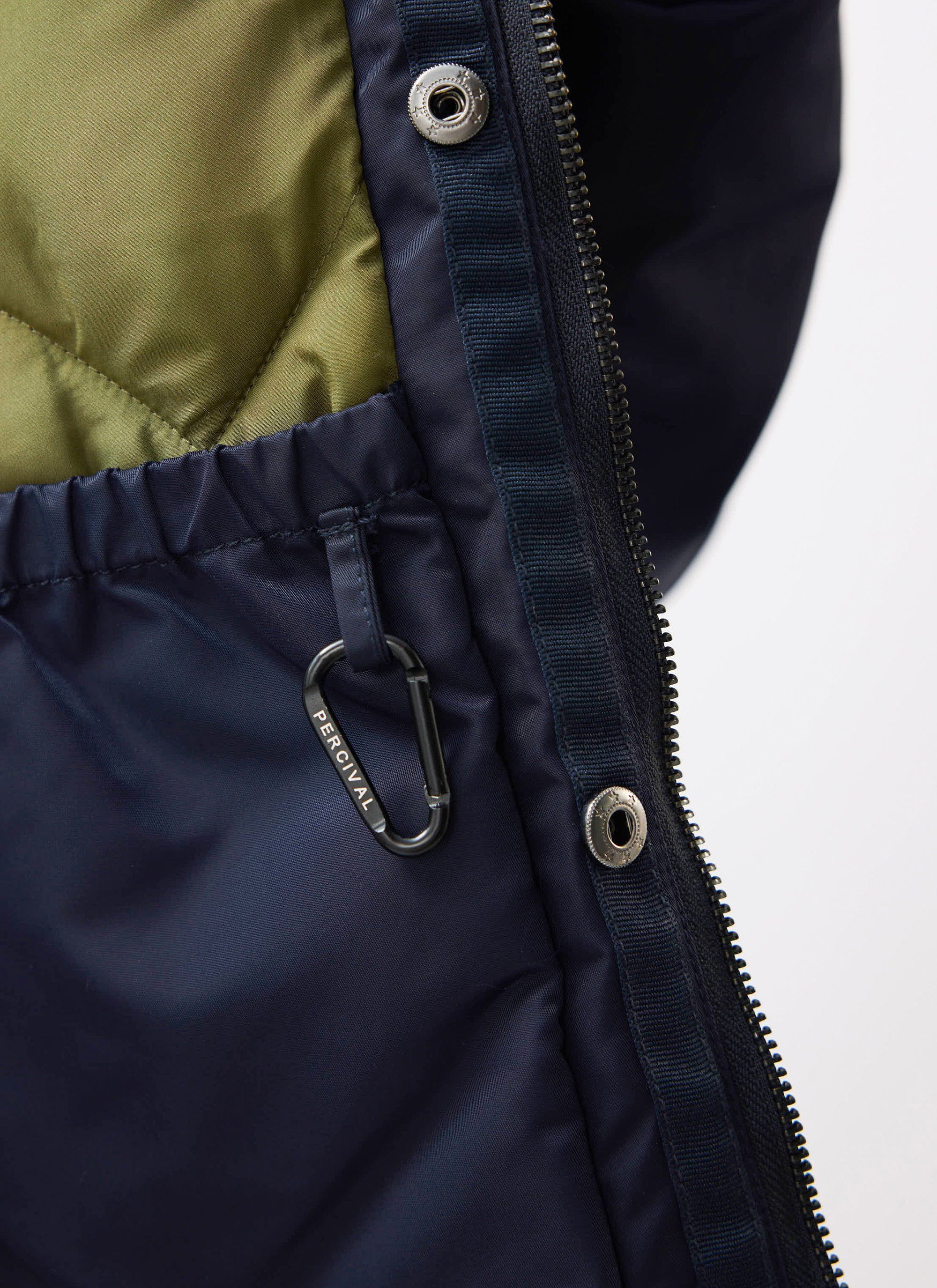 Close up of the Percival midnight navy bomber jacket's olive quilted lining, internal pocket and branded carabiner.