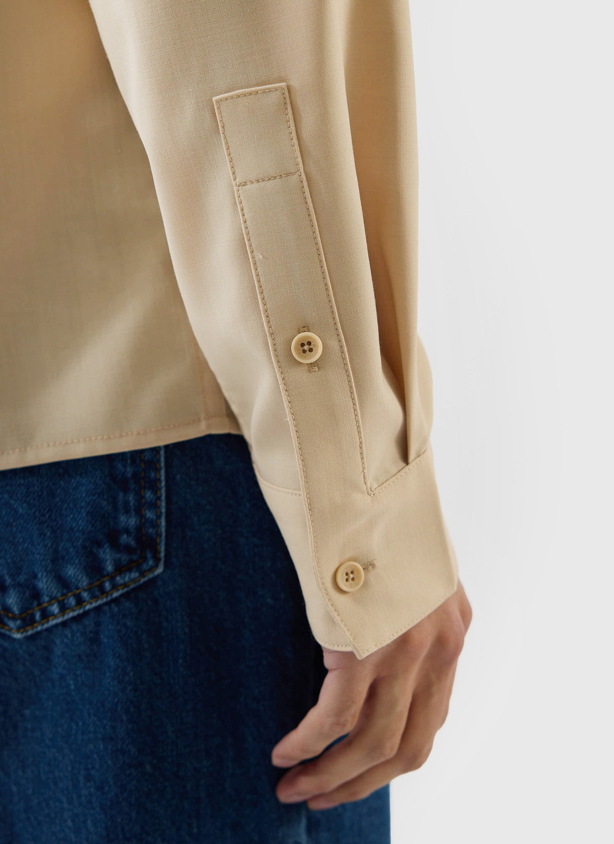 A close-up of the buttoned cuff and sleeve detail of the Percival x Warren Safari Shirt in camel beige.