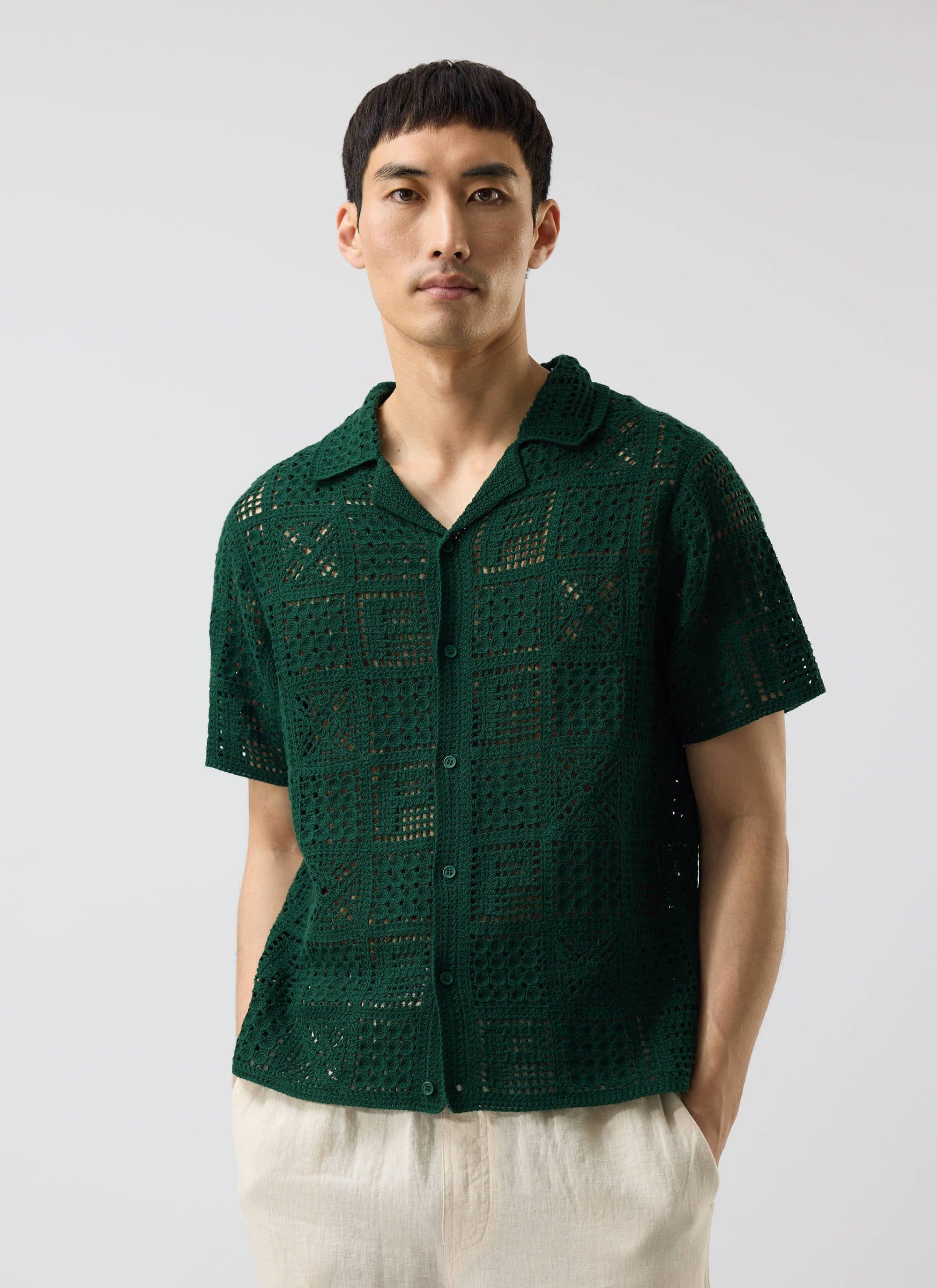 A model wears the Percival Crochet Groundsman Shirt in forest green, a short-sleeve button down with an open-knit design.