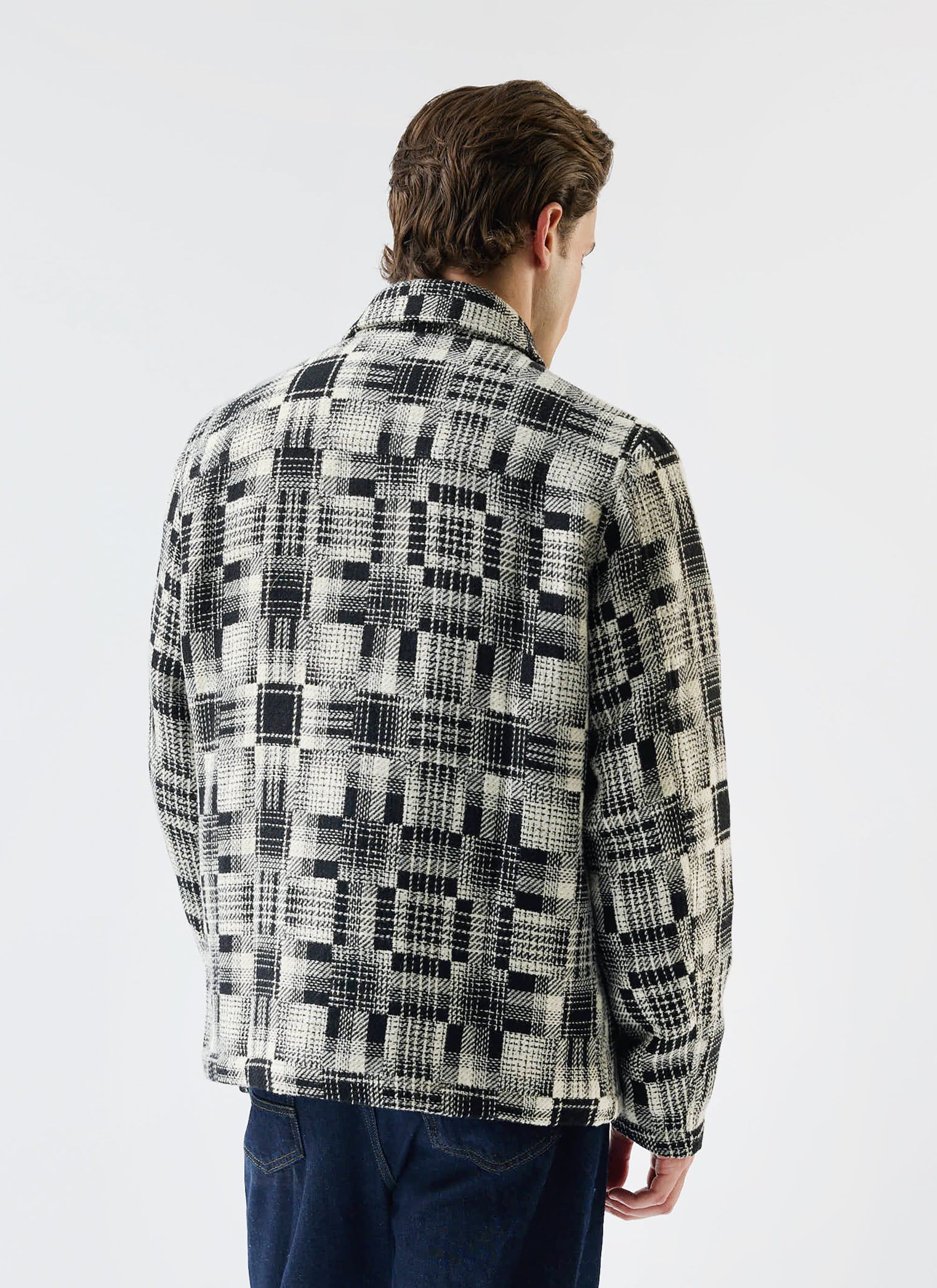 Rear view of a man modelling the grey twill Glossary Patchwork Jacket from Percival, showing the detailed pattern.