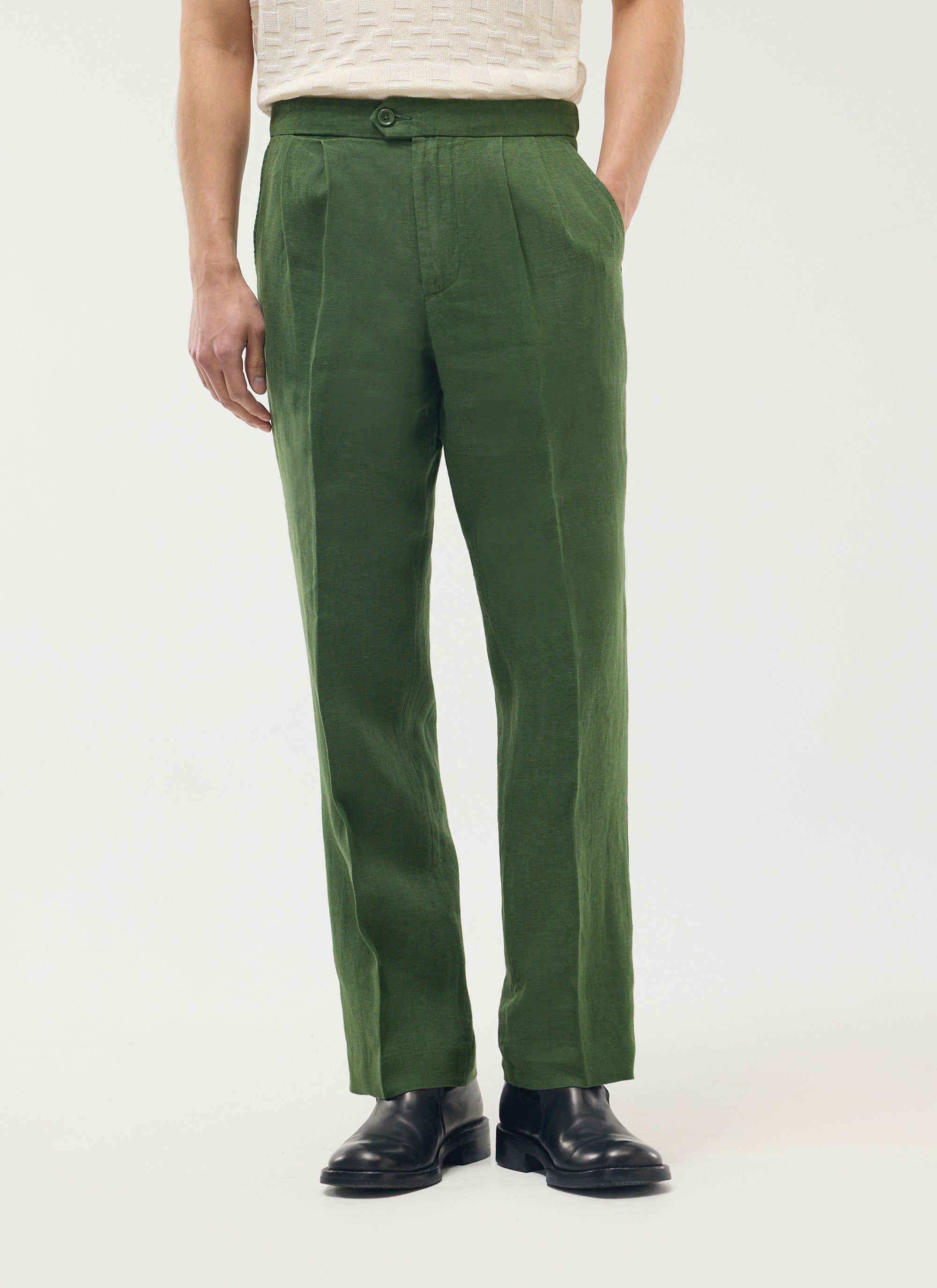 A model wears the Percival Pleated Tailored Trousers in forest green linen with a cream top and black shoes.