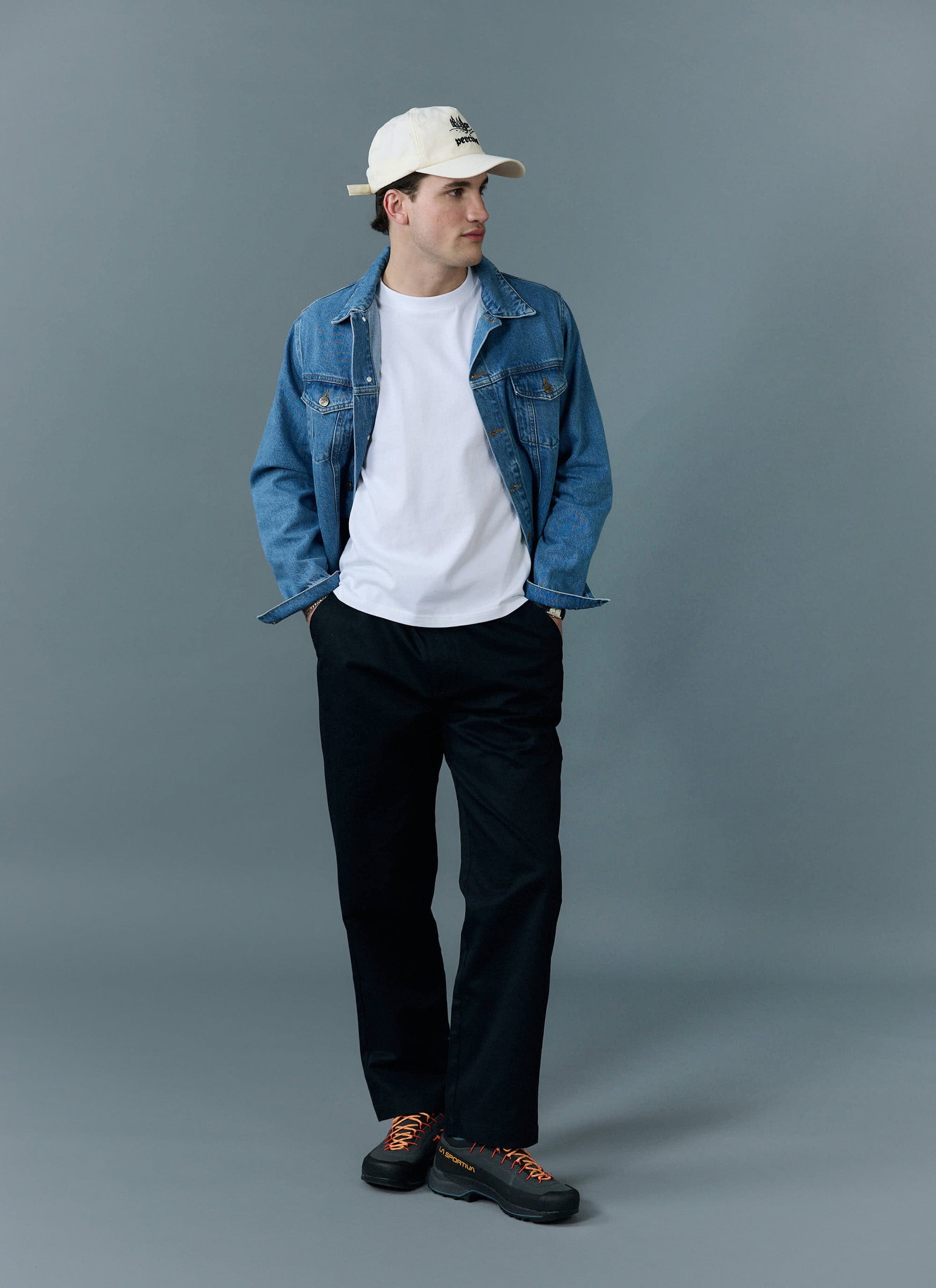 A man models the Percival Western Trucker Jacket in light wash blue, styled over a white t-shirt with black trousers.