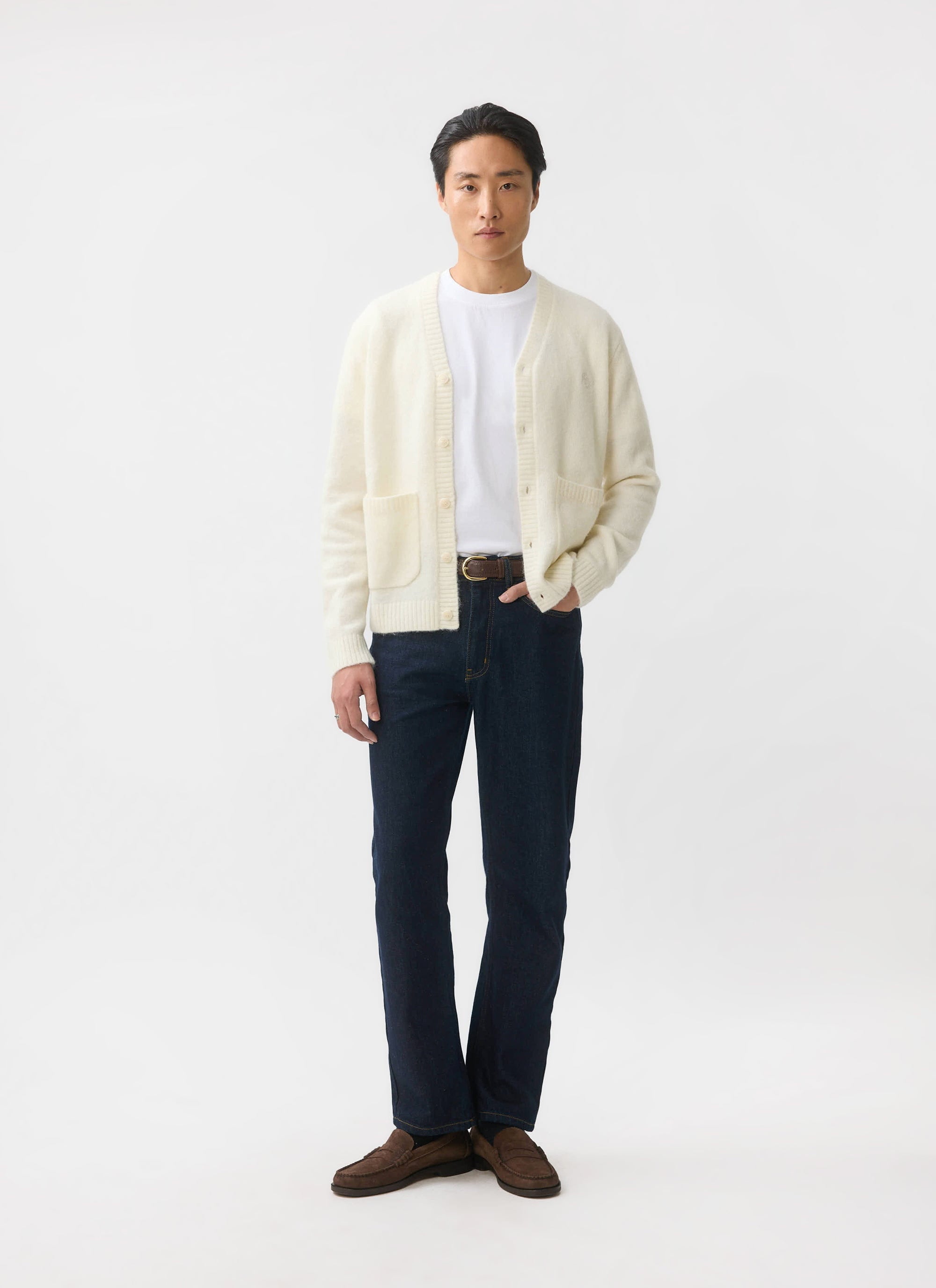 A man models the ecru mohair White Glove Cardigan from Percival, styled with dark jeans against a white backdrop.