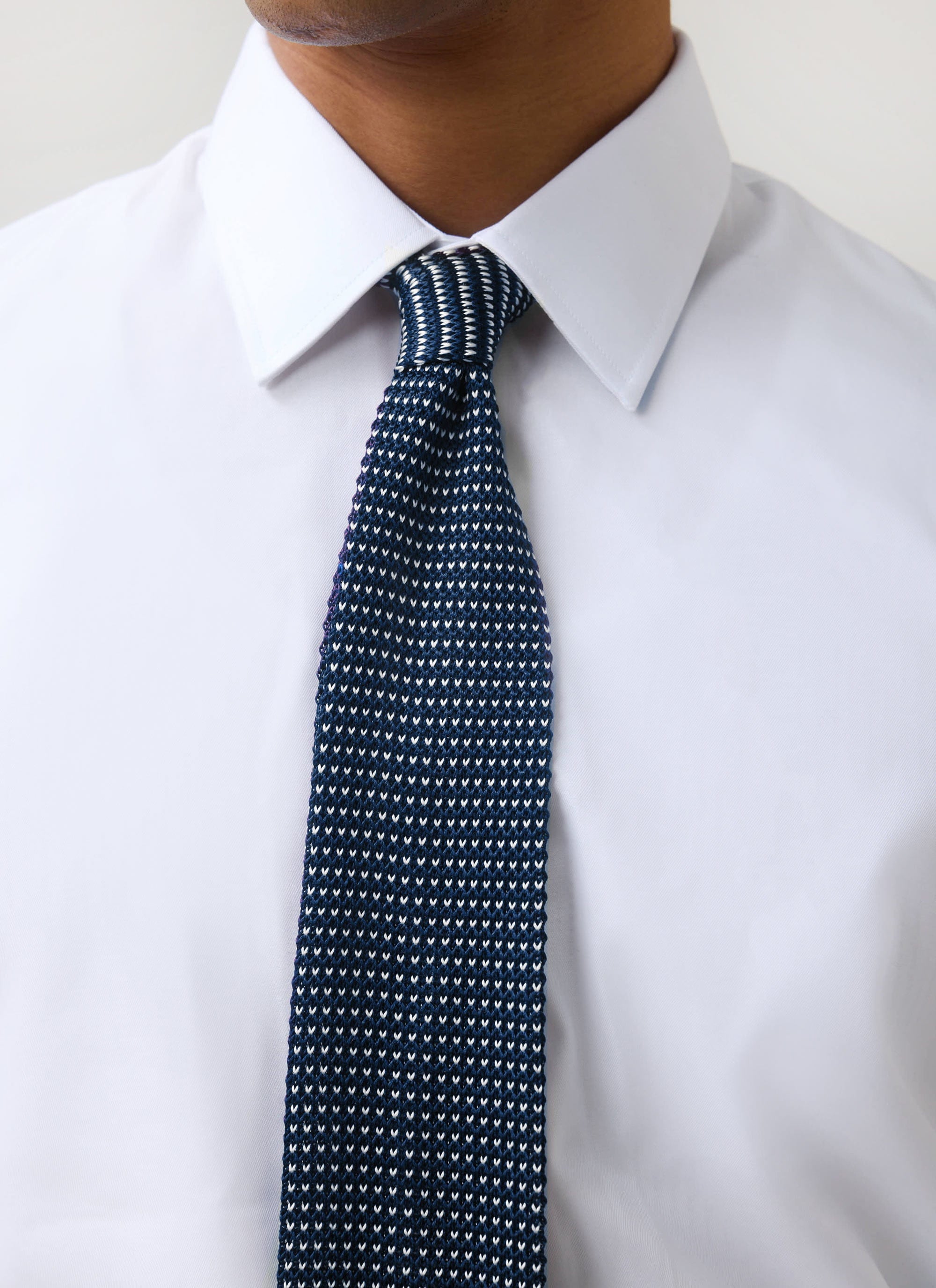 A close-up of a model wearing the blue Birdseye Silk Tie from Percival, paired with a crisp white shirt.