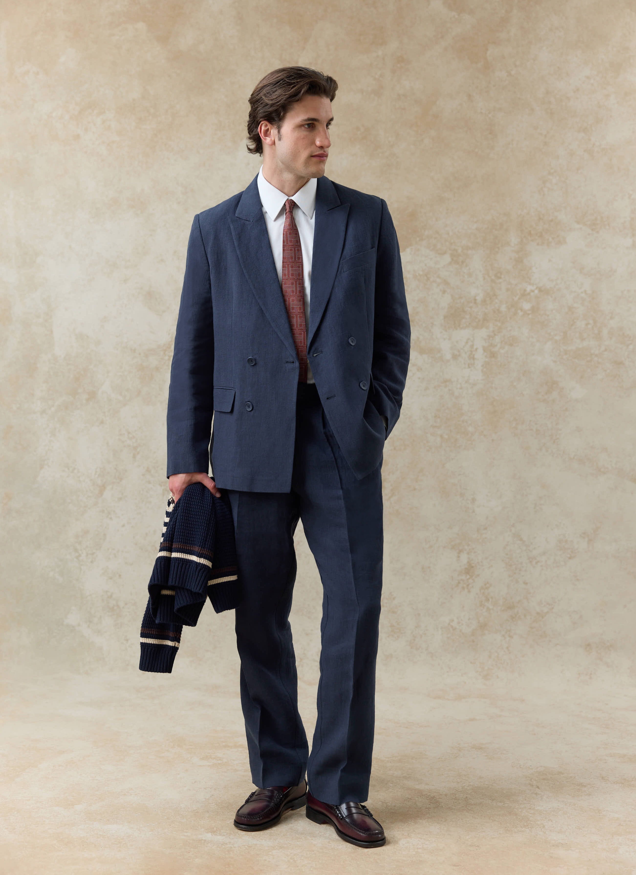 Navy blue linen pleated tailored trousers by Percival, styled with a matching double-breasted blazer and patterned tie.