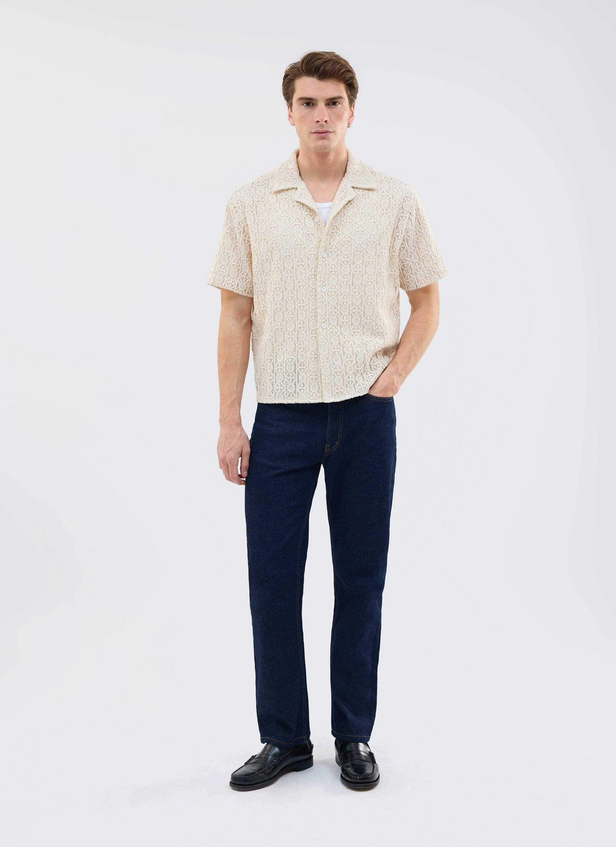 A model wears the Percival Elio Crochet Cuban Shirt in ecru, styled with dark denim jeans and black loafers.